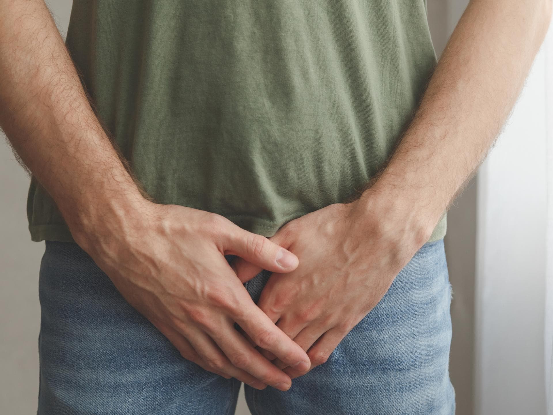 Mann hält Hand vor Schritt