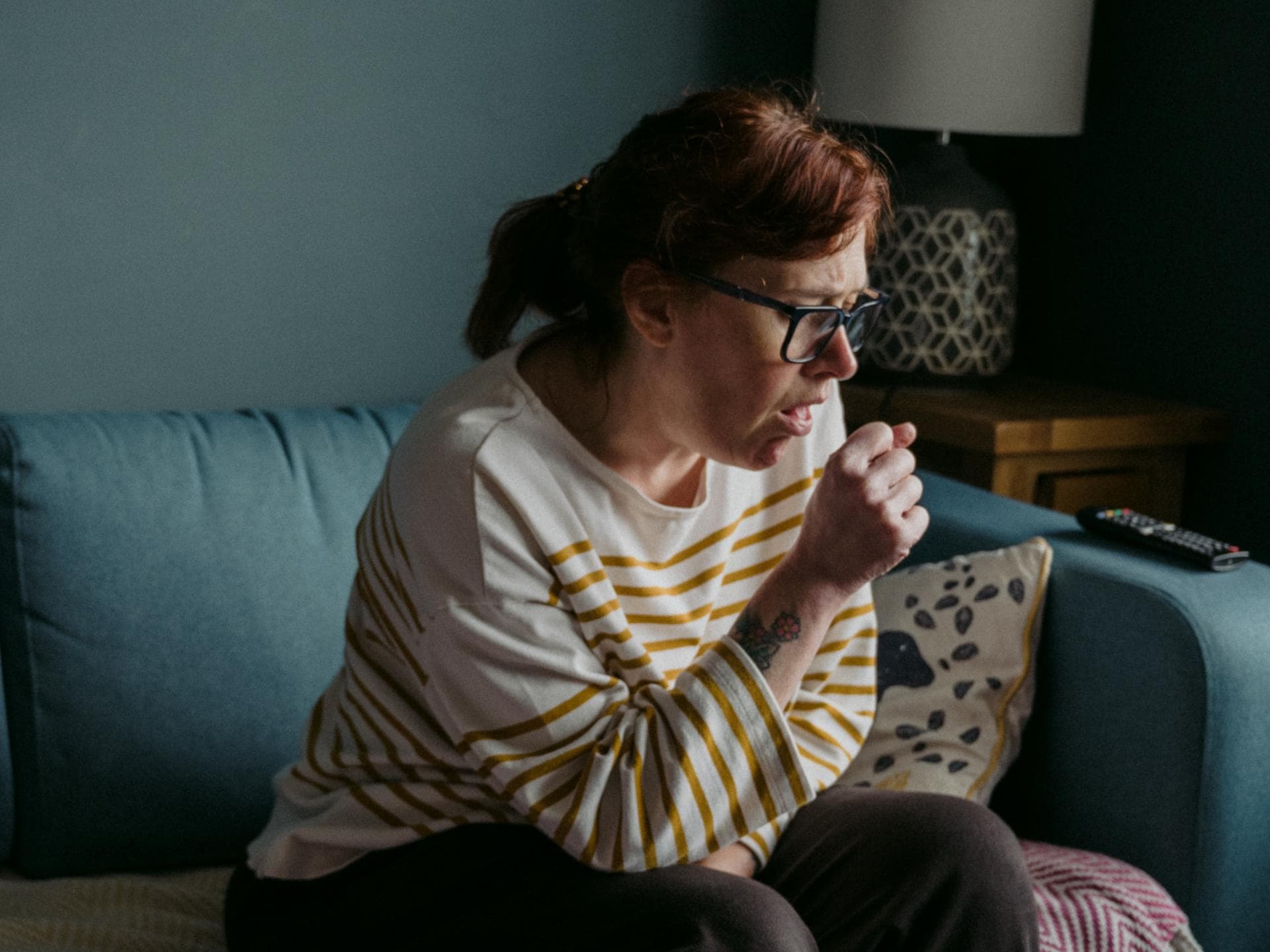 Frau hustet auf Couch