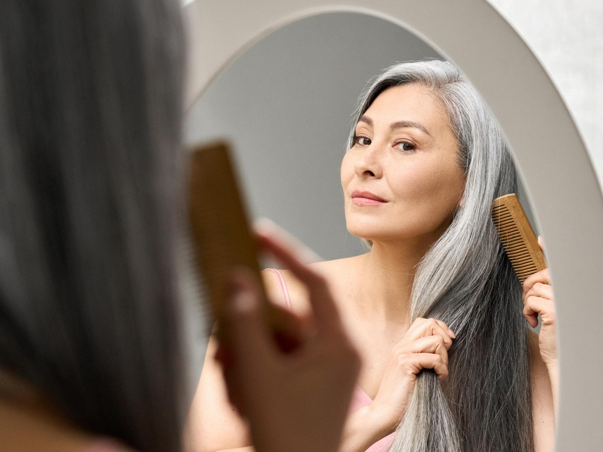 Frau kämmt graue Haare