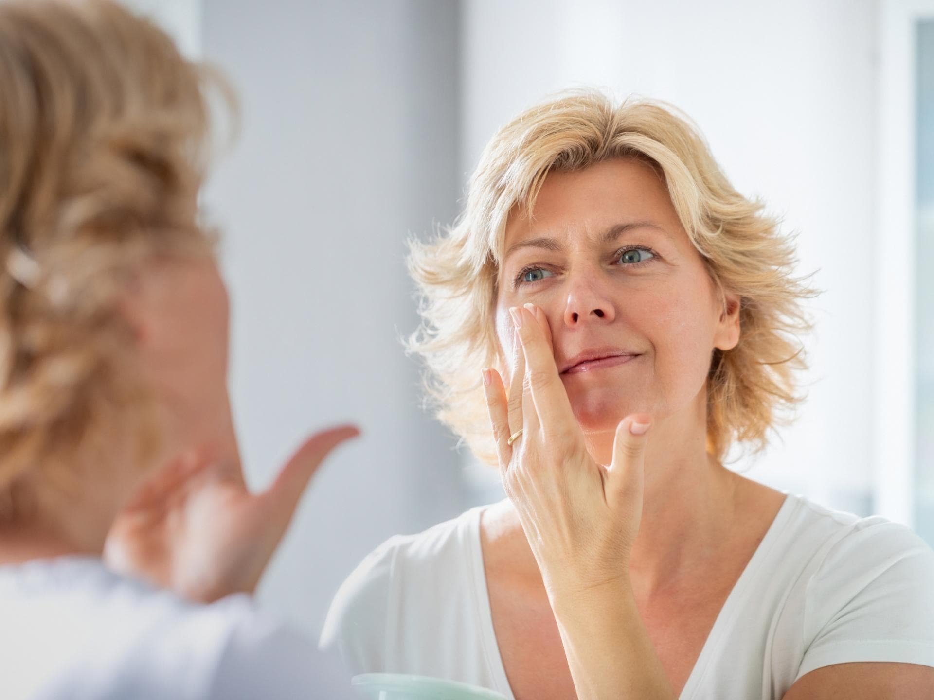 Frau cremt Gesicht ein