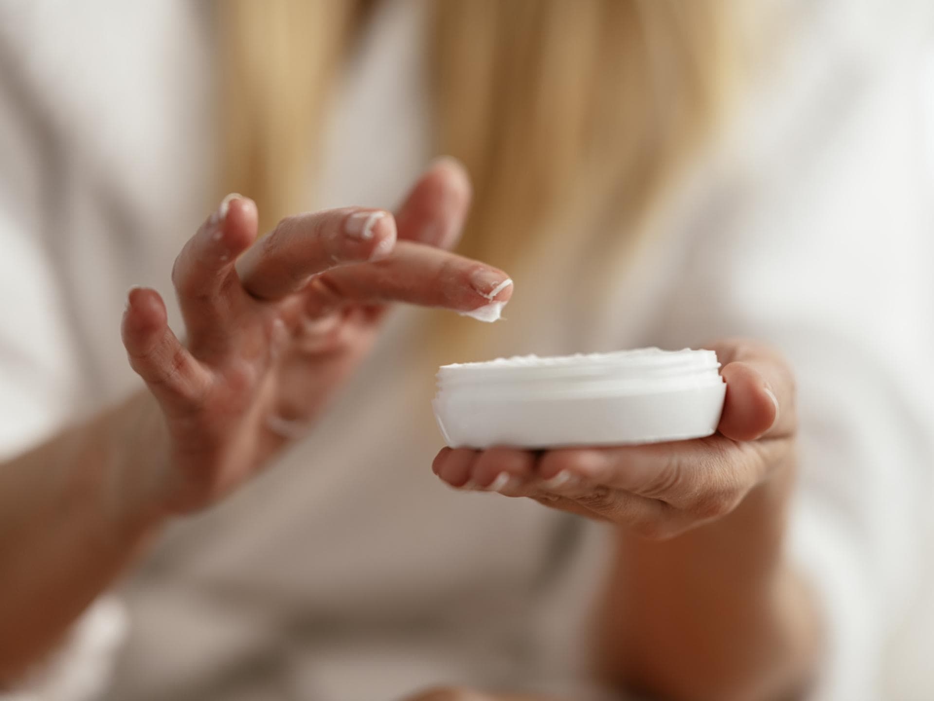 Frau nimmt Creme aus Tigel 