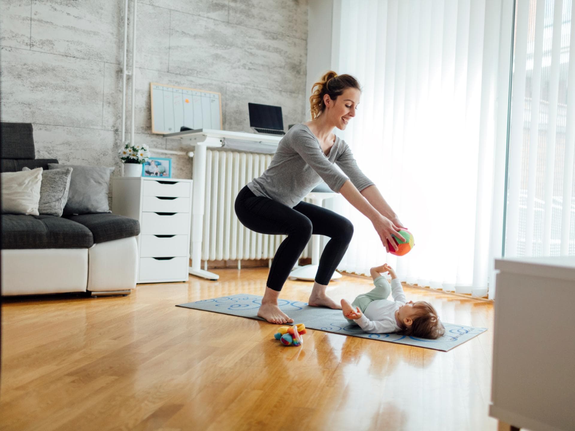 Mutter macht Kniebeuge beim Spielen mit Kind