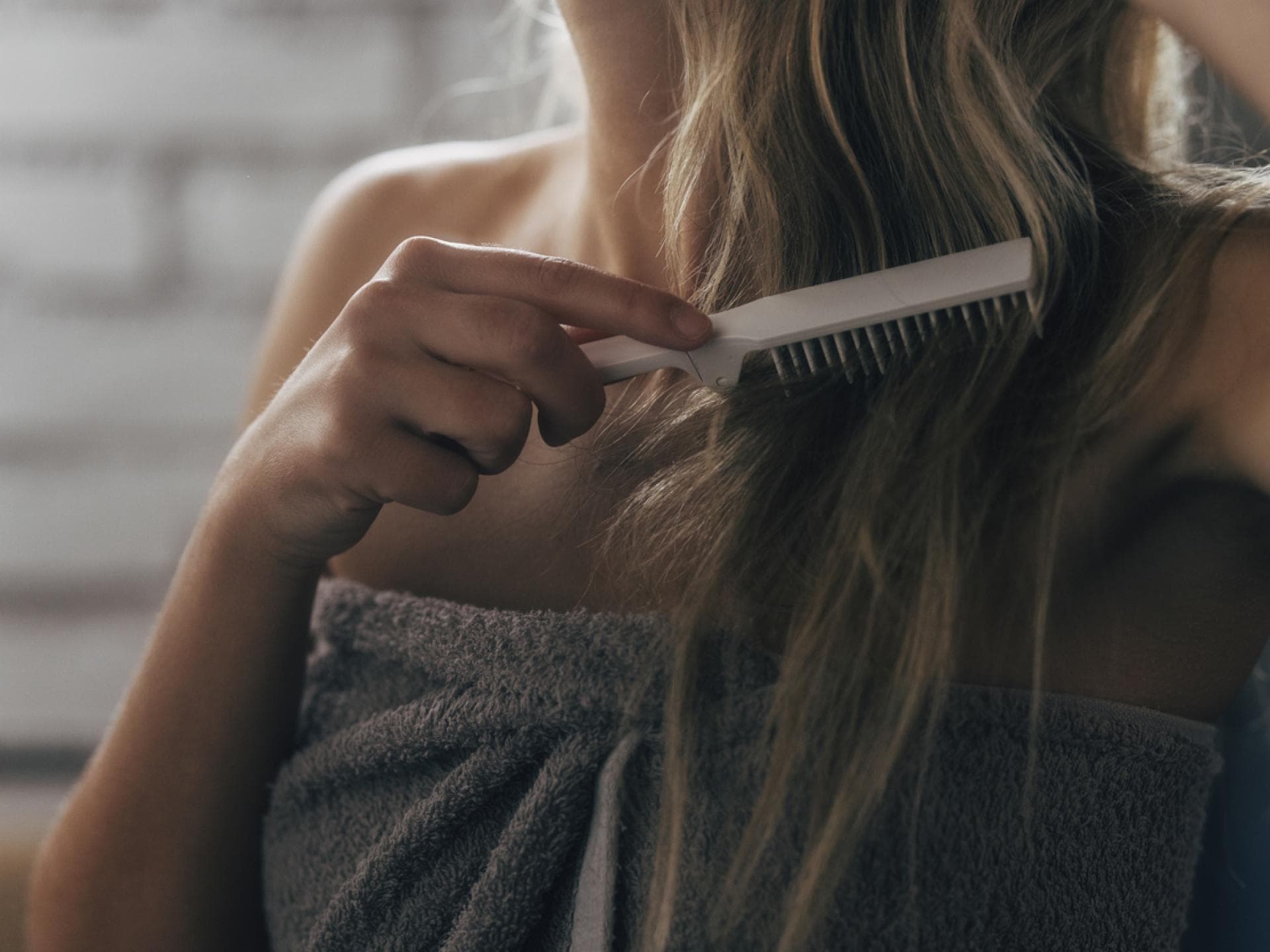 Frau kämmt sich Haare nach der Dusche