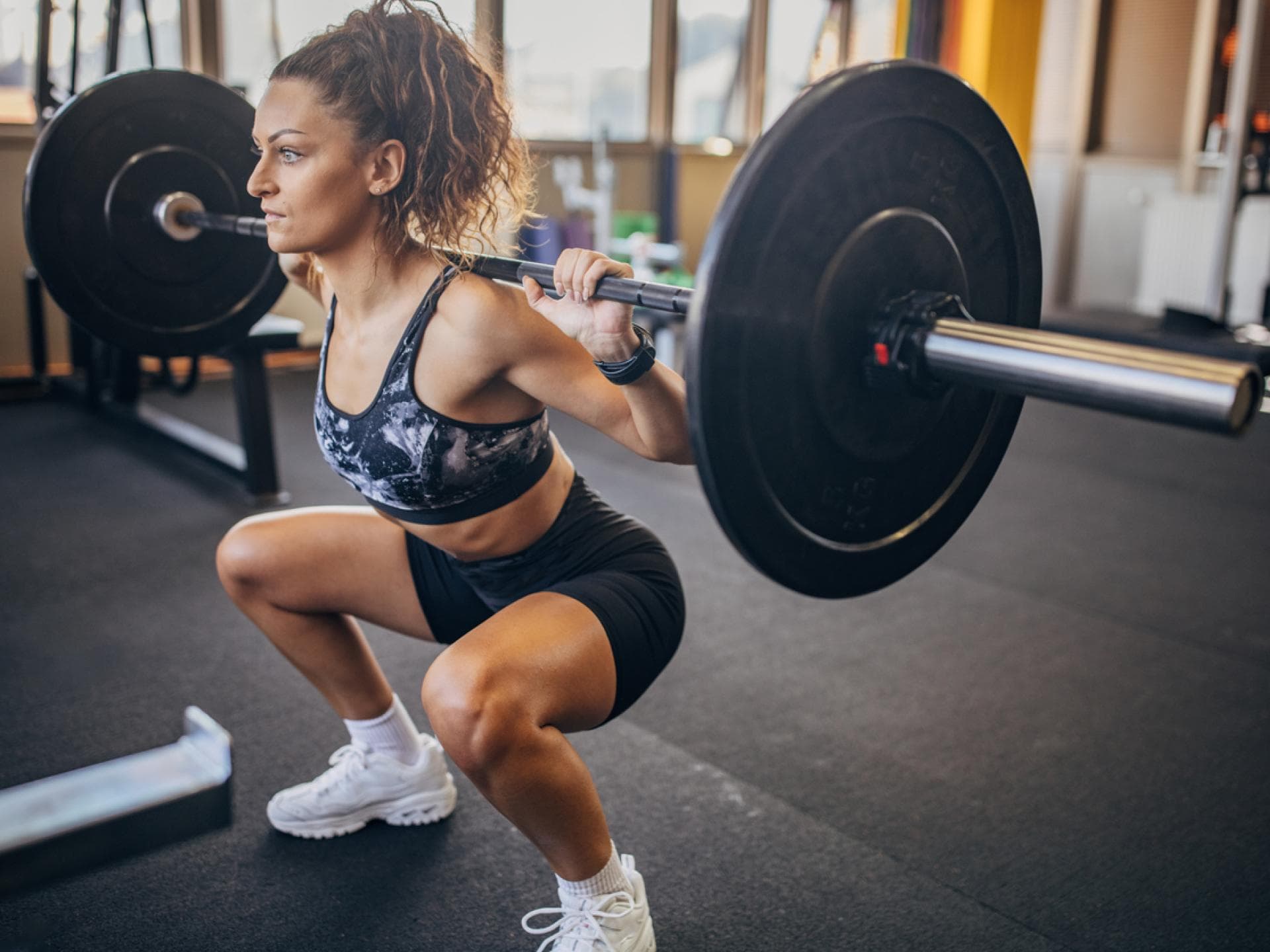 Frau mit Langhantel macht Squats