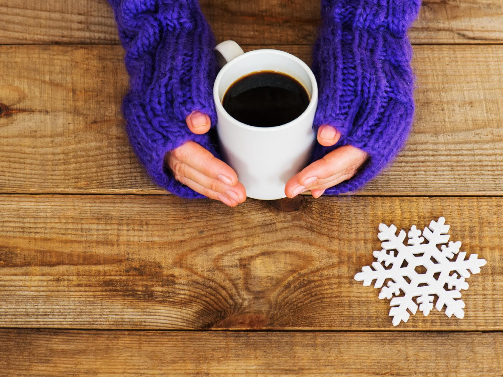Frau wärmt Hände an einer Tasse Kaffee