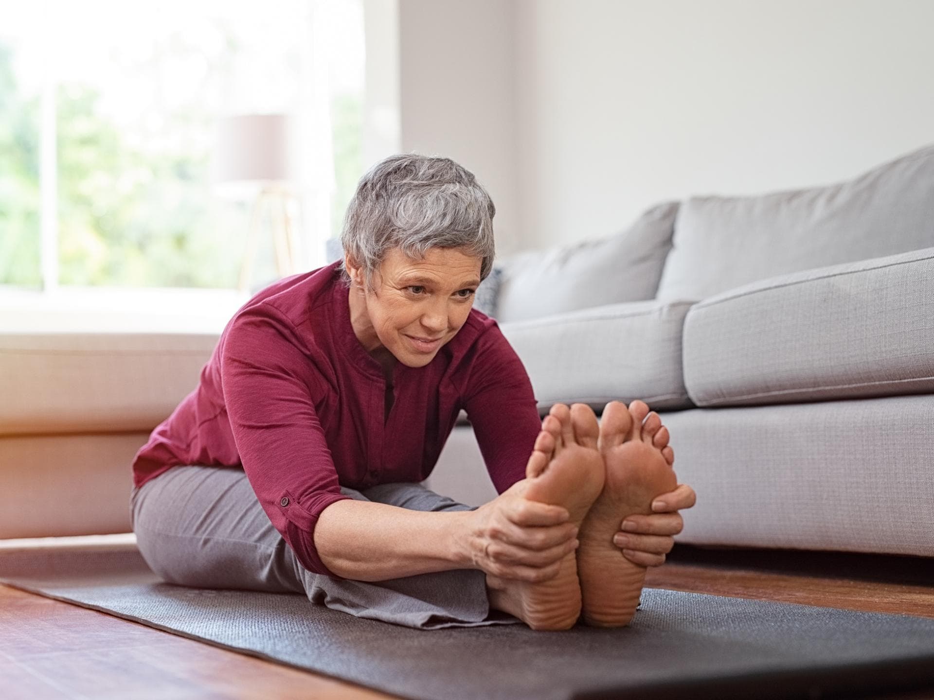 Ältere Frau dehnt sich auf Yogamatte