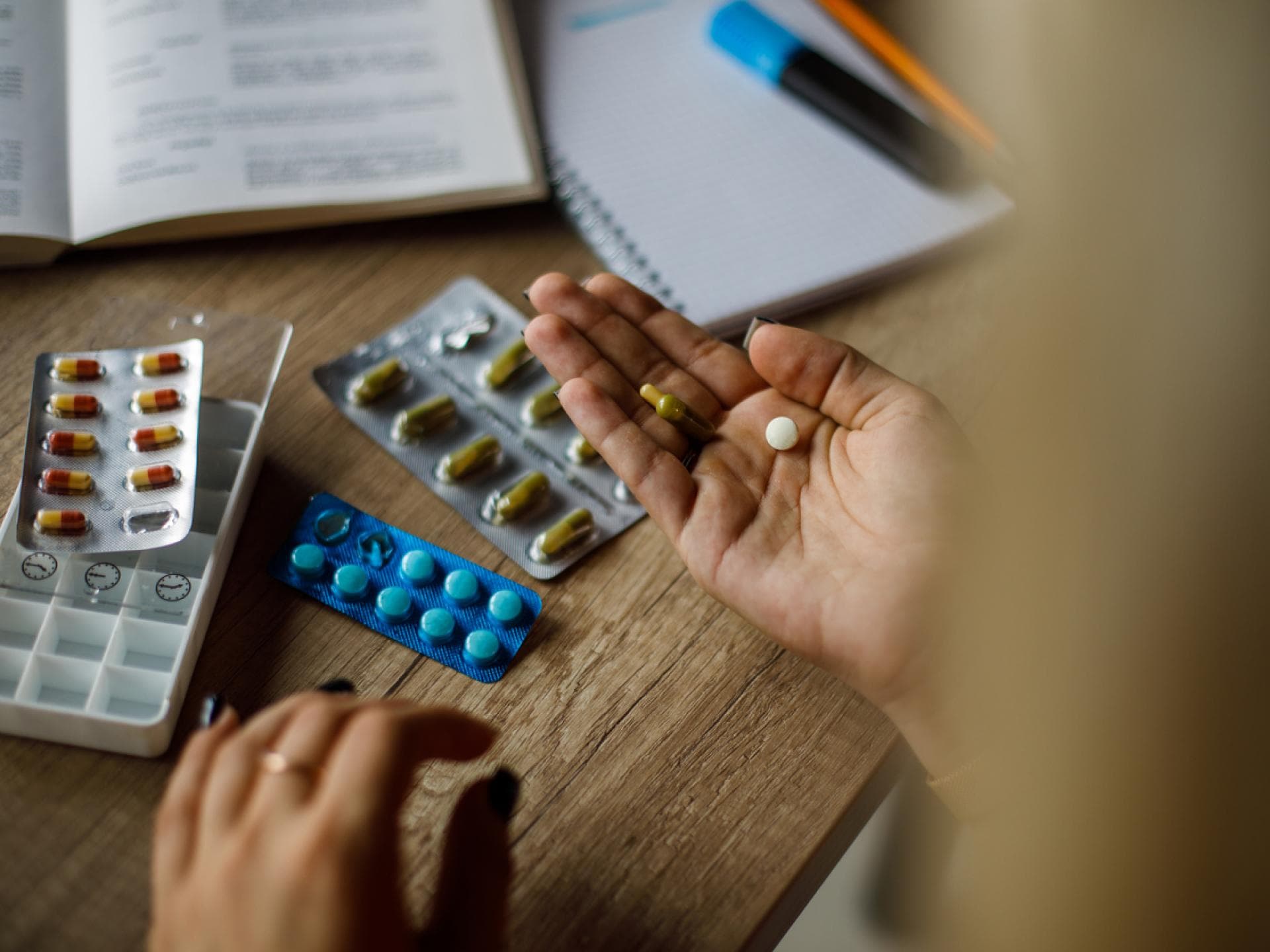 Frau hat verschiedene Filmtabletten vor sich liegen