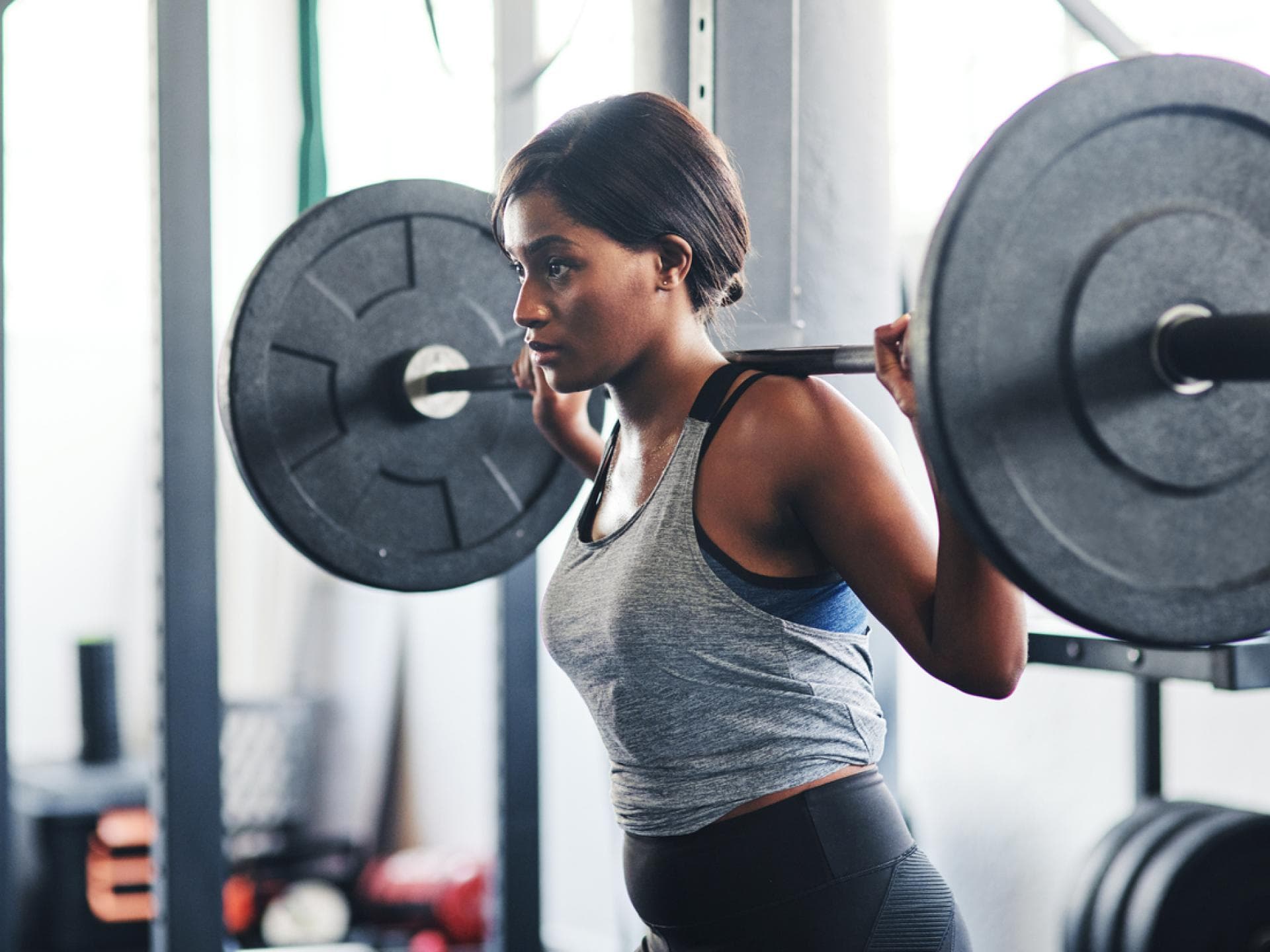 Frau macht Back-Squats im Squat-Rack