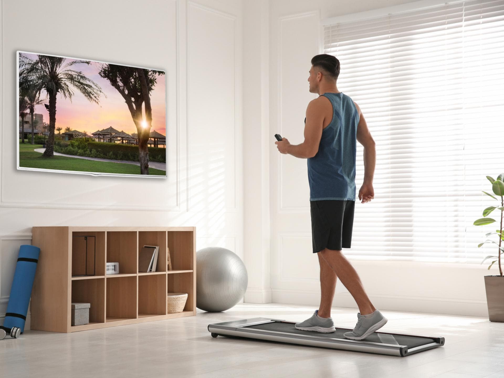 Mann geht auf kleinem Laufband im Wohnzimmer spazieren