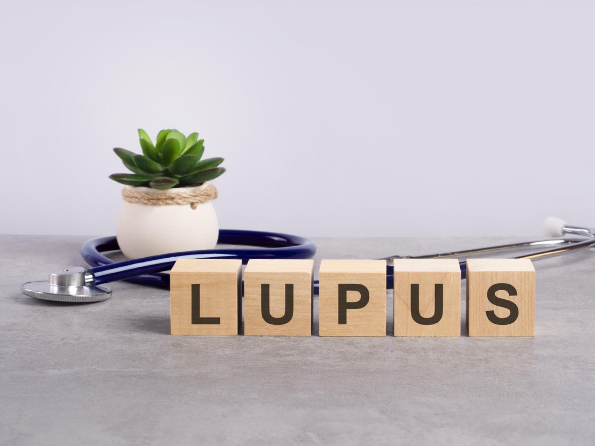 Bei Lupus Erythematodes (SLE) schwellen die Lymphknoten ebenfalls an. Buchstabenklötzchen auf Tisch mit Stetoskop