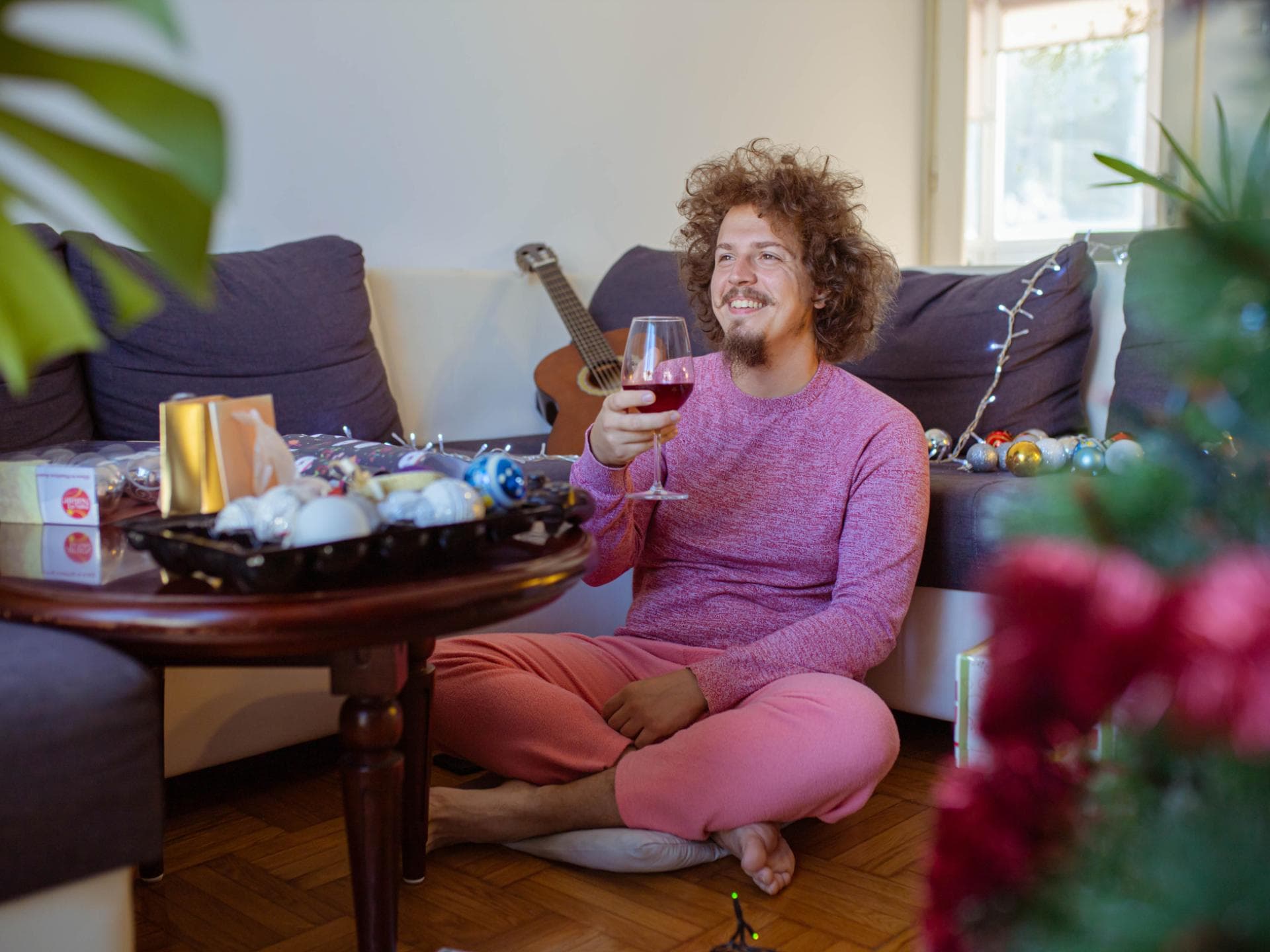 Mann sitzt mit Weinglas alleine vor dem Fernseher