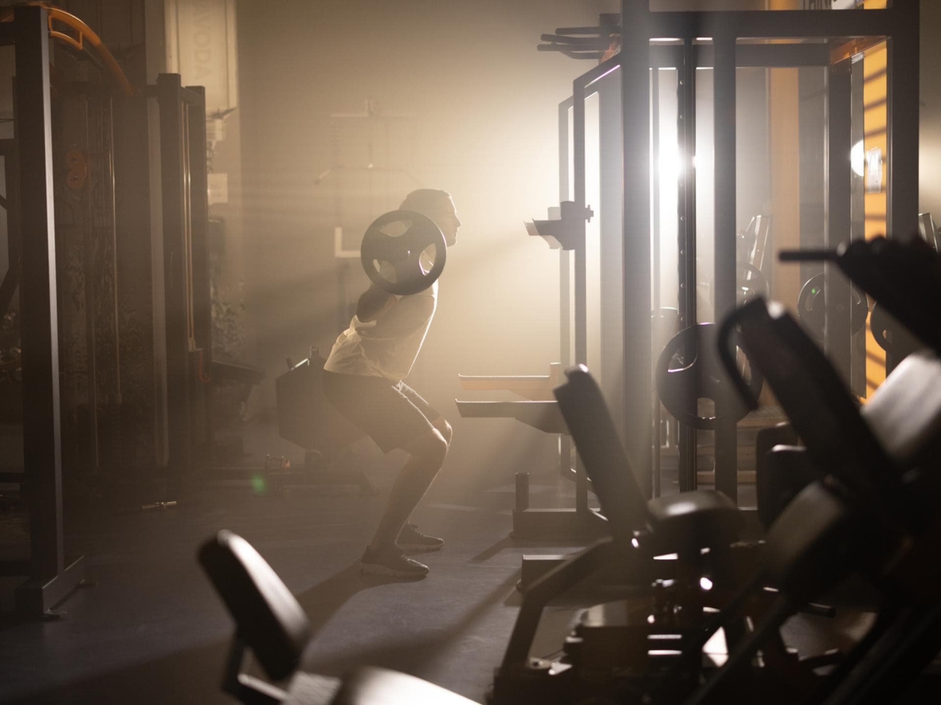 Mann macht Squats im Gym bei Sonnenaufgang
