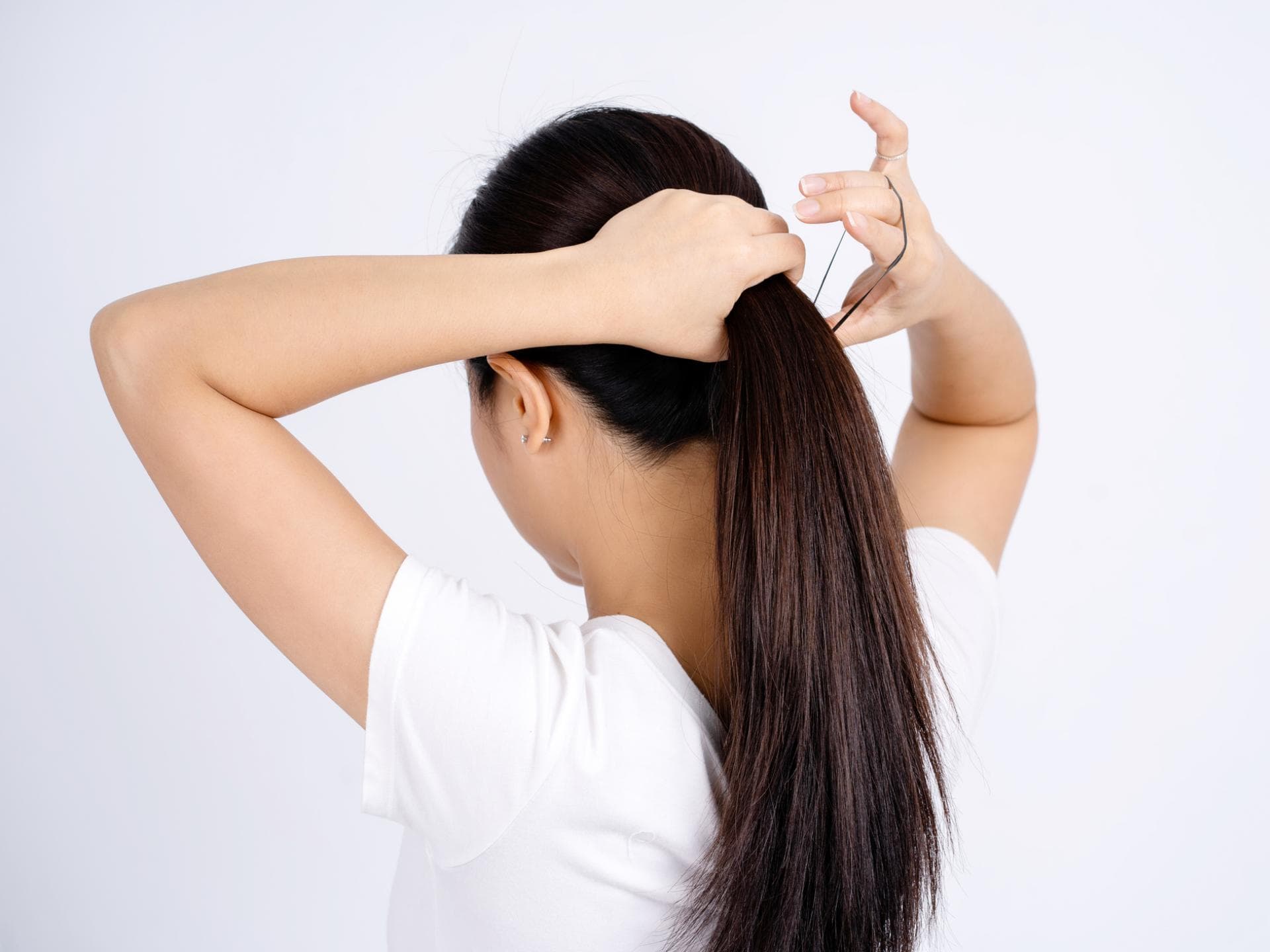 Frau bindet Haare zusammen