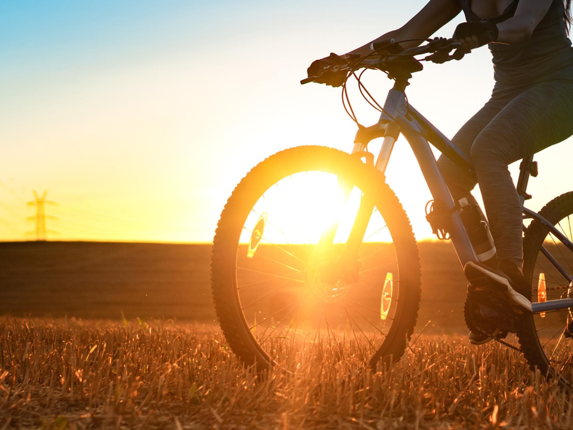 Frau fährt in der Abendsonne auf dem Fahrrad