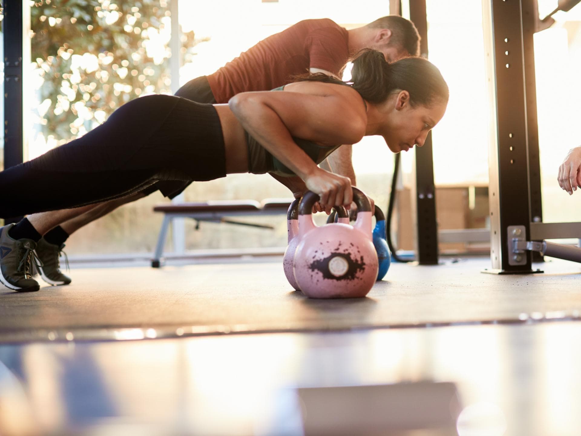 Liegestützt mit Griffen oder Kugelhantel Frau macht Liegestütz mit Kettlebells