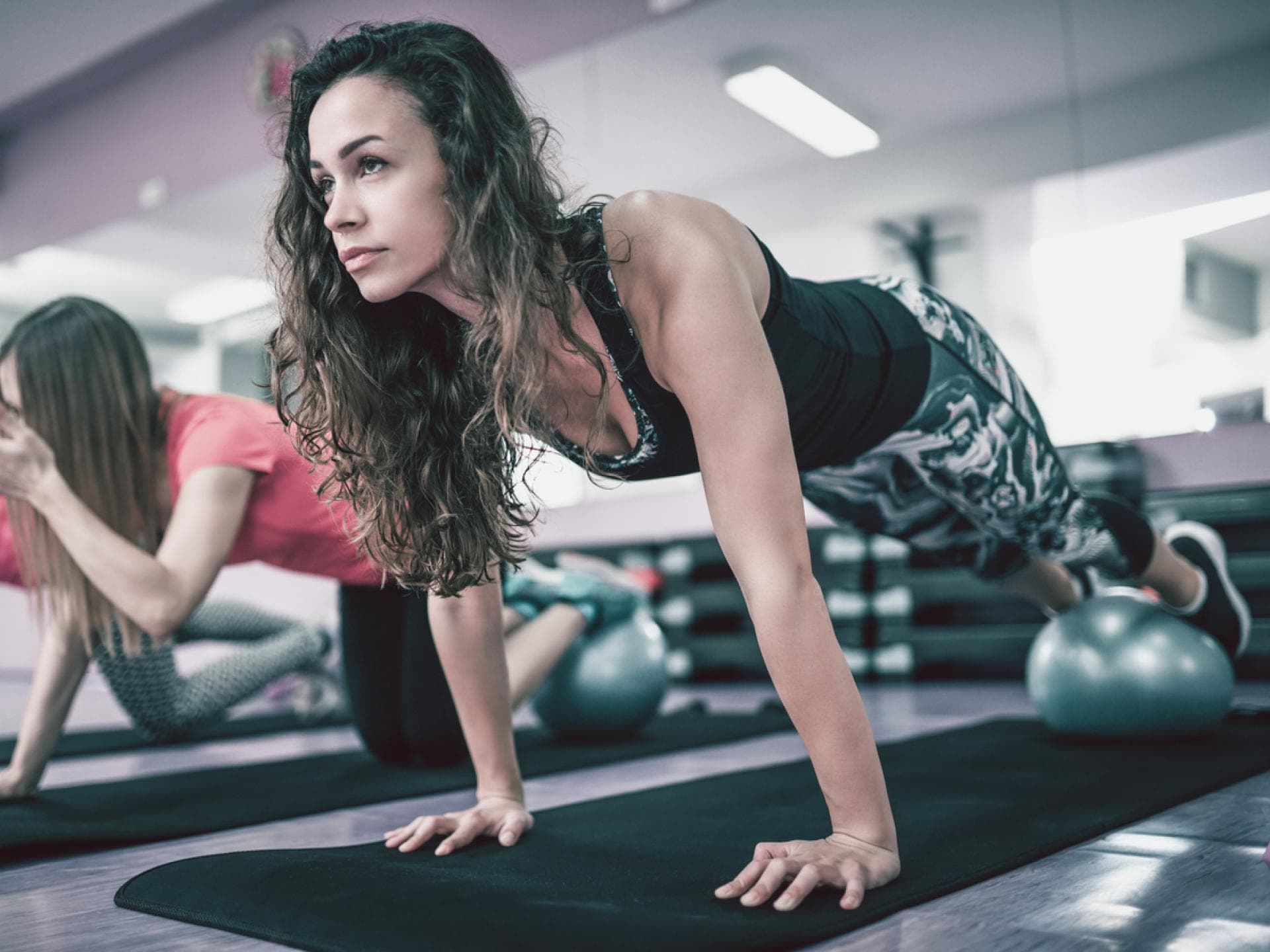 Push-ups mit erhöhten Beinen Frau macht Liegestütz auf Gymnastikball