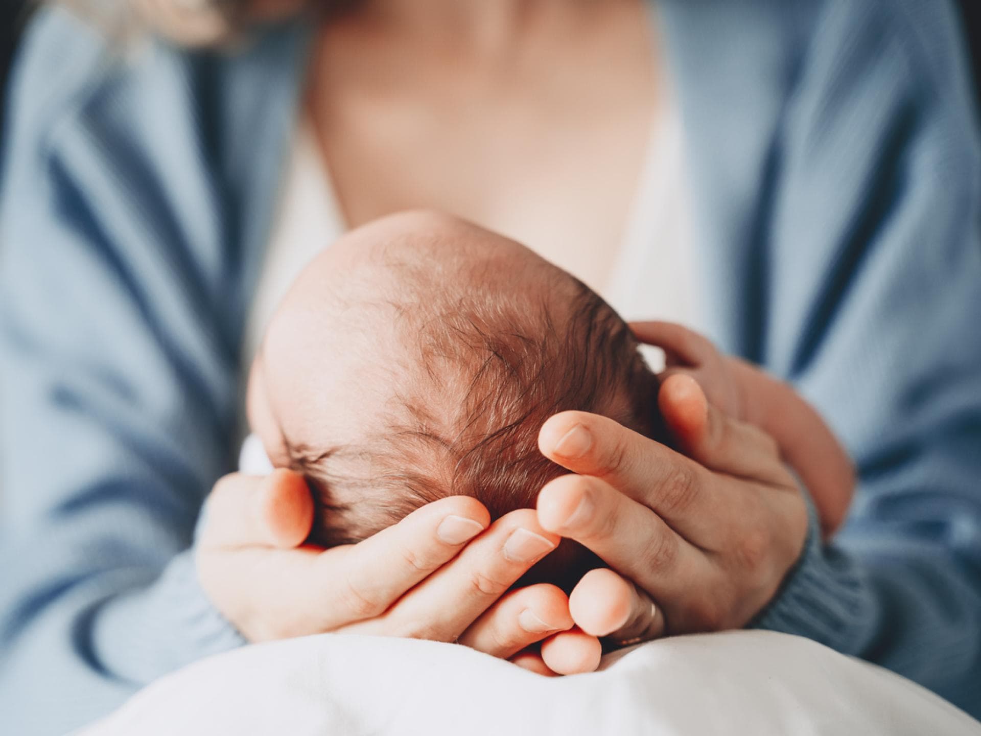 Mutter hält Neugeborenes in der Hand