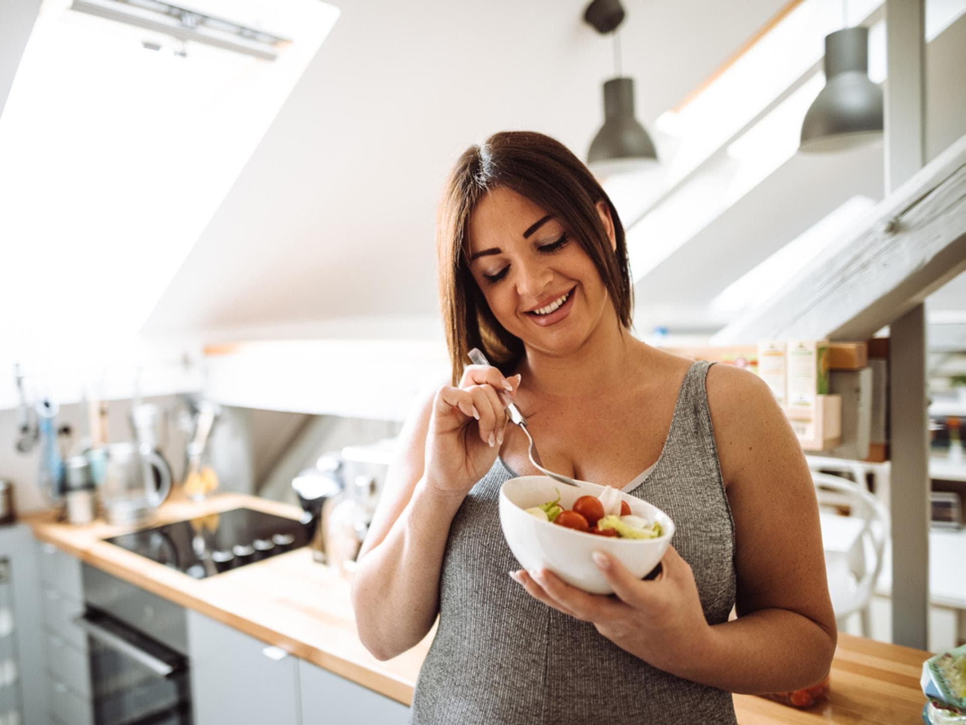 Schwangere Frau isst Obst in Küche