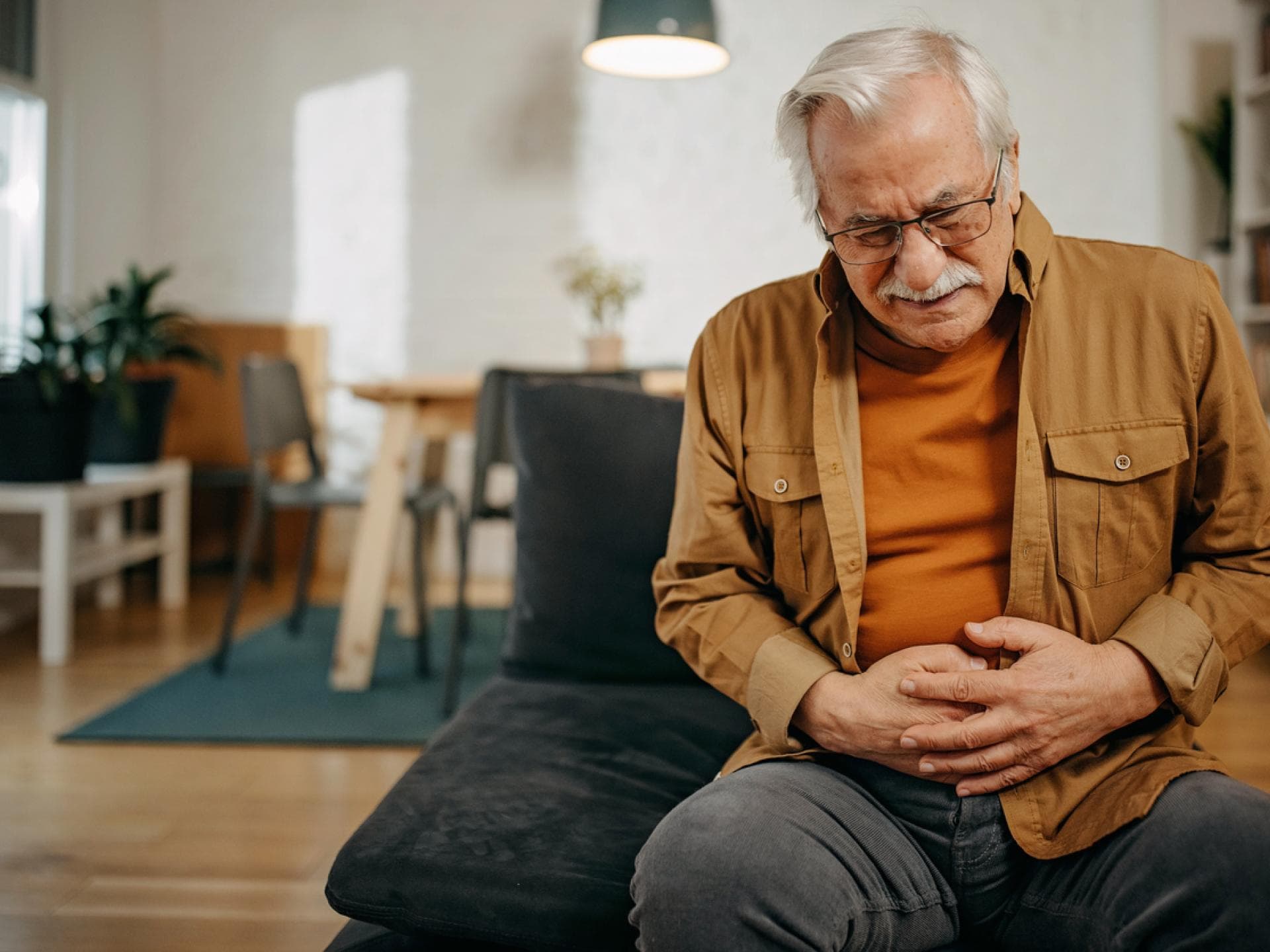 Älterer Mann hält sich schmerzenden Unterbauch