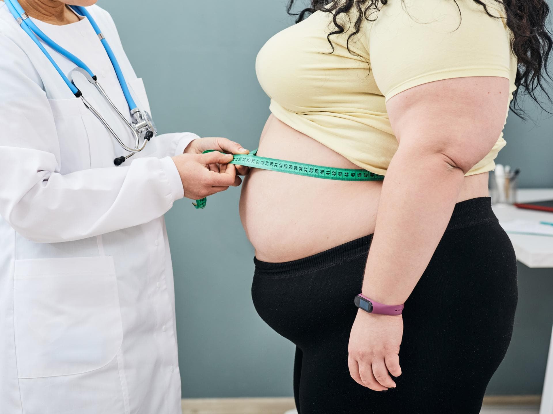 Ärztin misst Bauchumfang einer übergewichtigen Patientin.