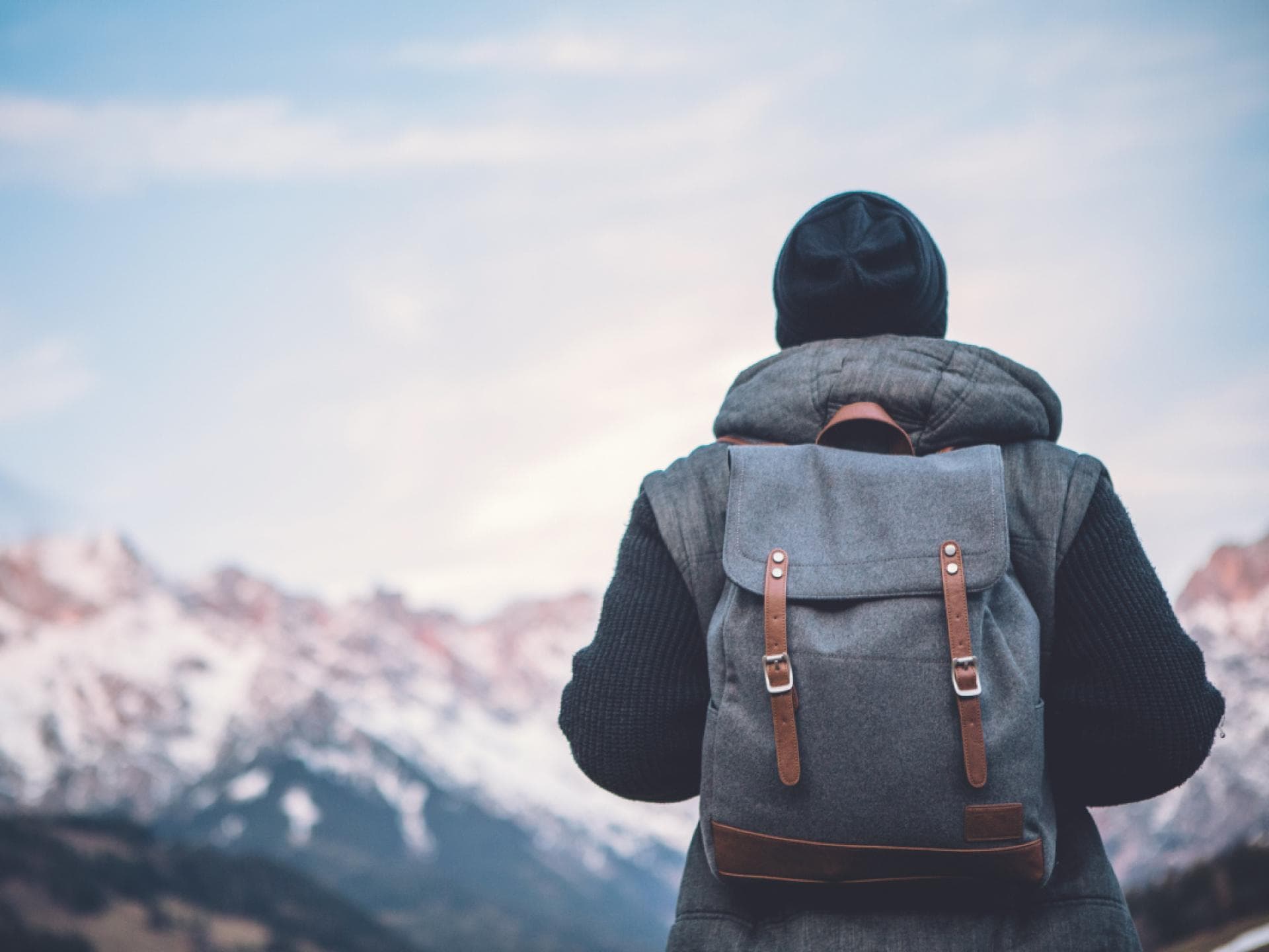 Mann mit Rucksack blickt auf winterliche Berglandschaft