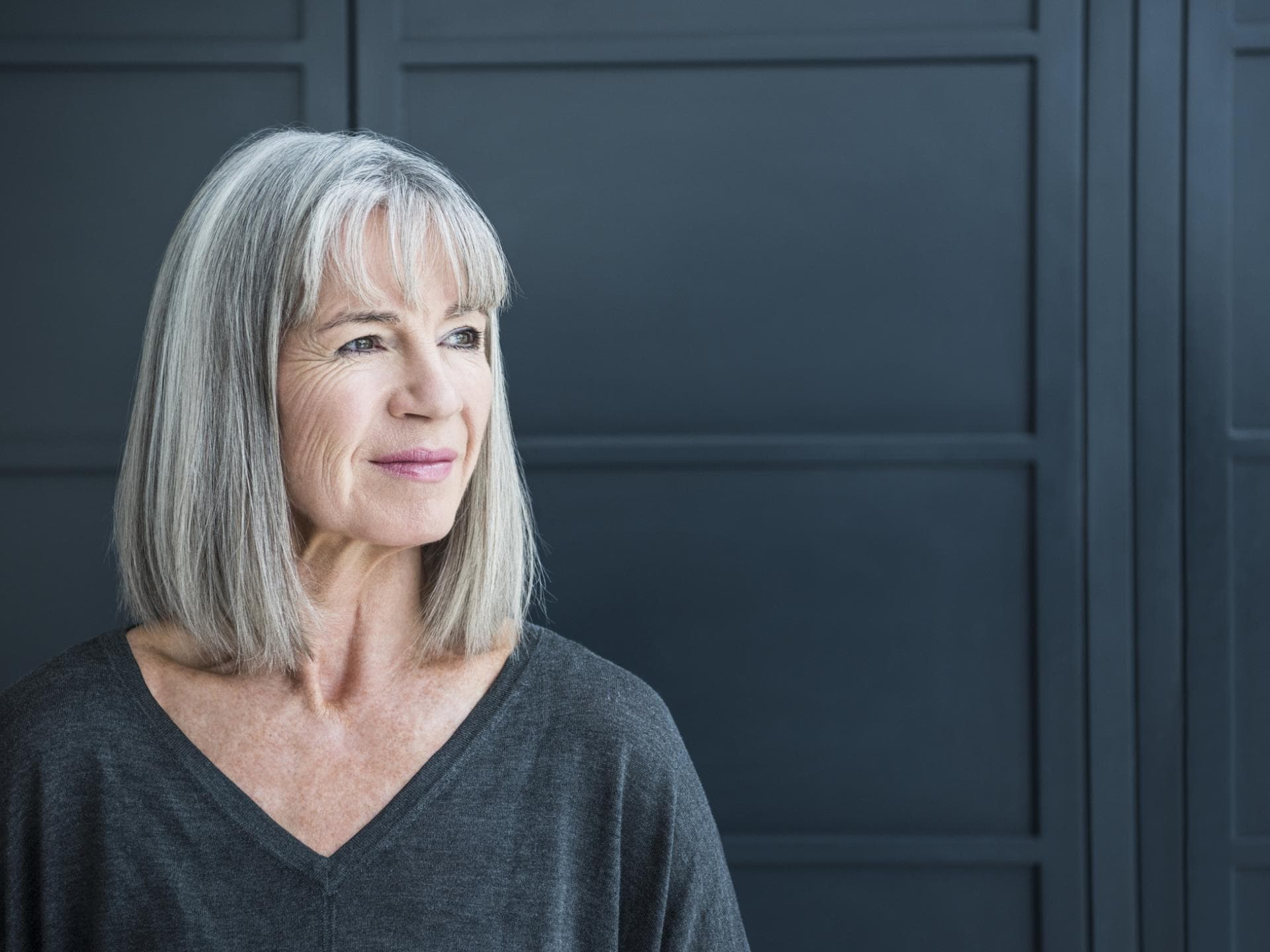 Frau mit grauen Haaren trägt einen Long Bob mit Pony Frau mit grauen Haaren trägt einen Long Bob mit Pony