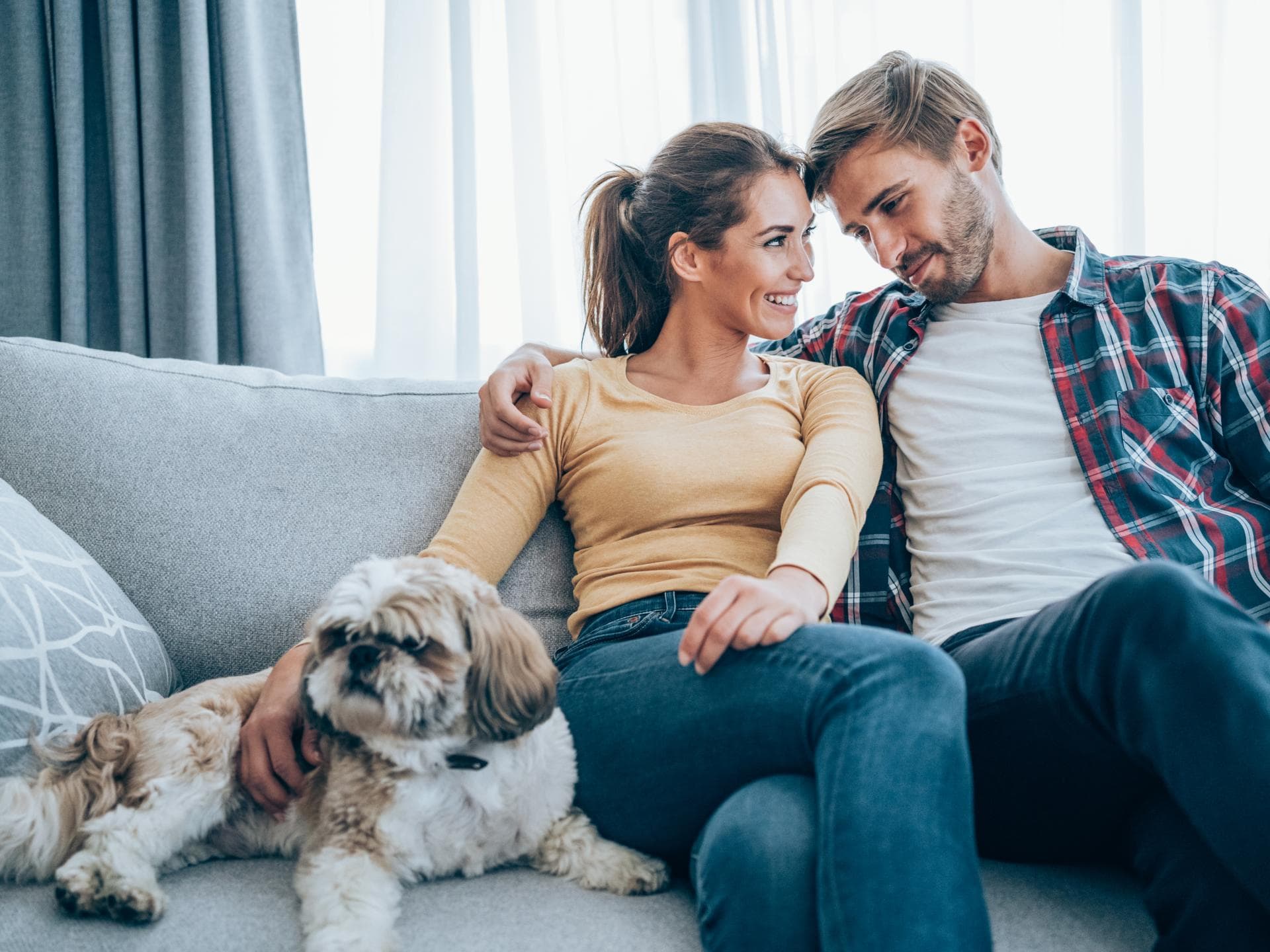 Ein glückliches Paar sitzt zusammen mit ihrem Hund auf der Couch