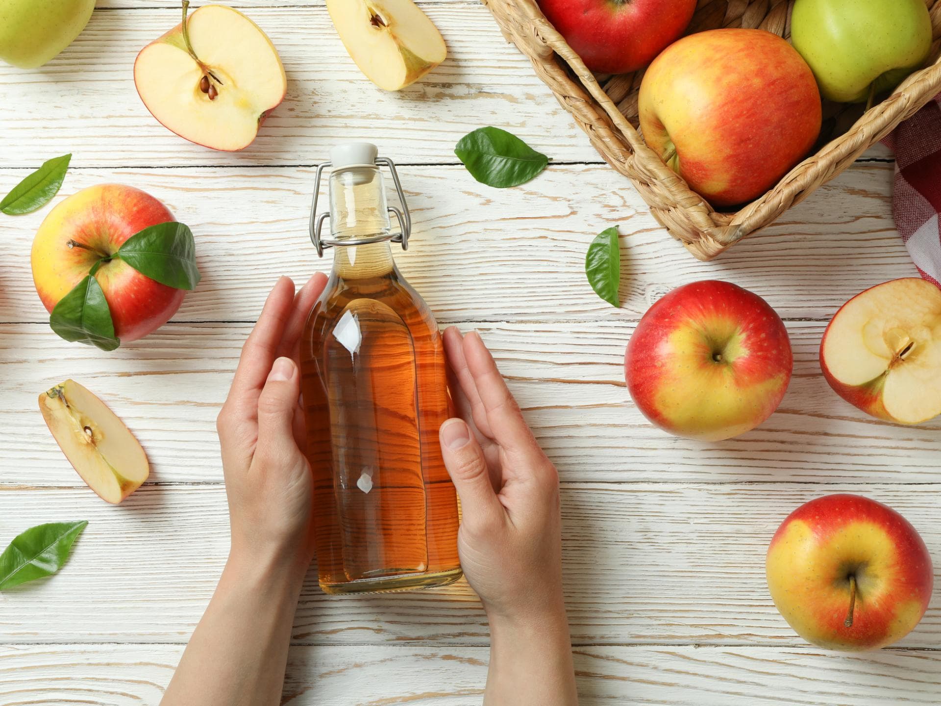 Frau hält Flasche mit Apfelessig in den Händen