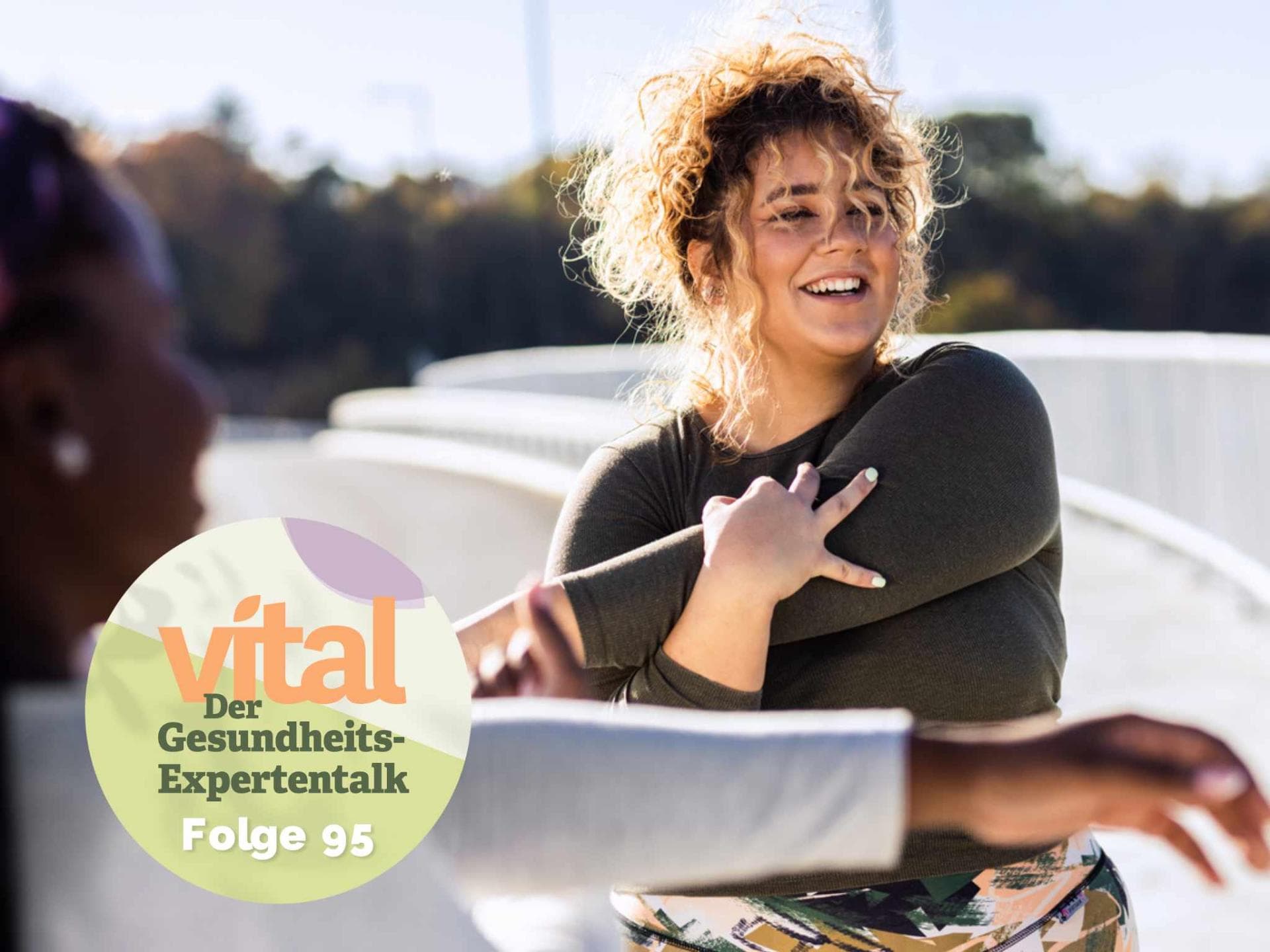 Zwei junge und übergewichtige Frauen dehnen sich vor einer Sporteinheit im Freien