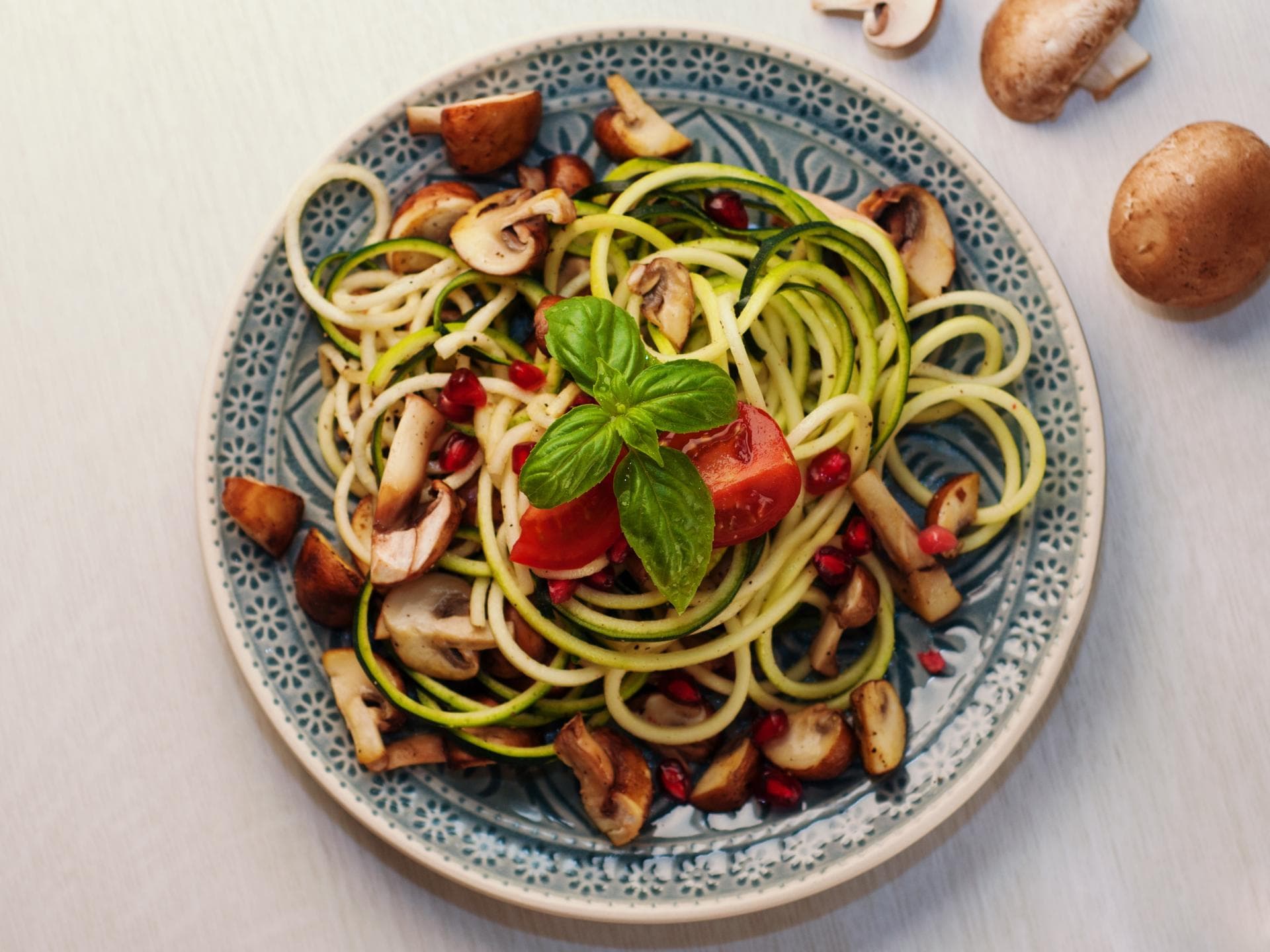 Rohe Zucchini in einem Salat mit Pilzen und Tomaten