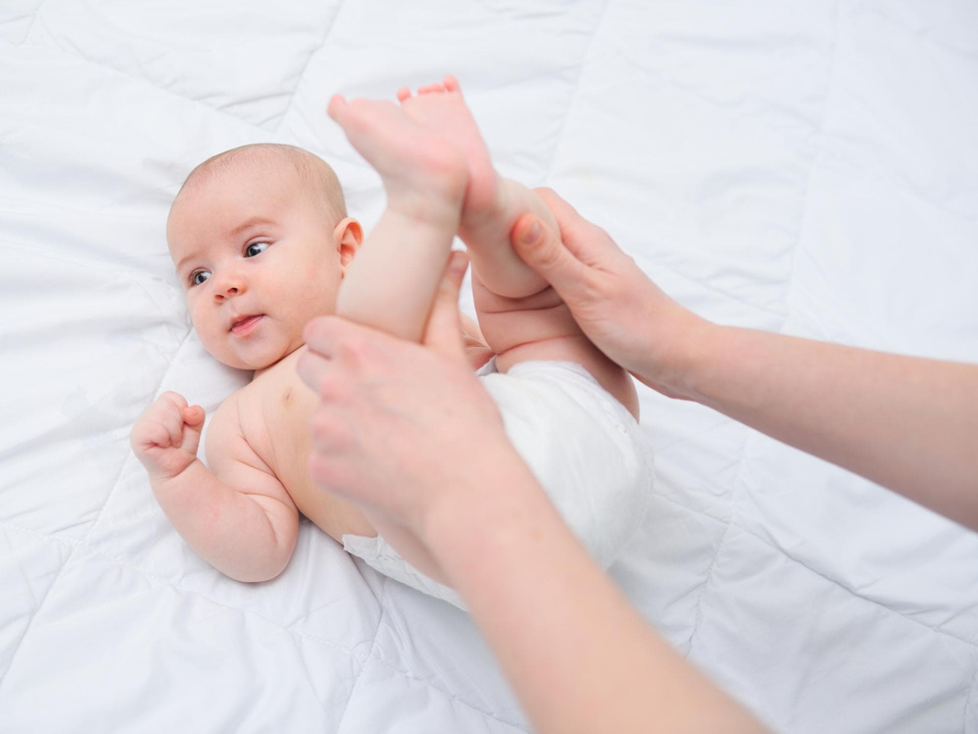 Ein Baby hat Bauchschmerzen und wird massiert.