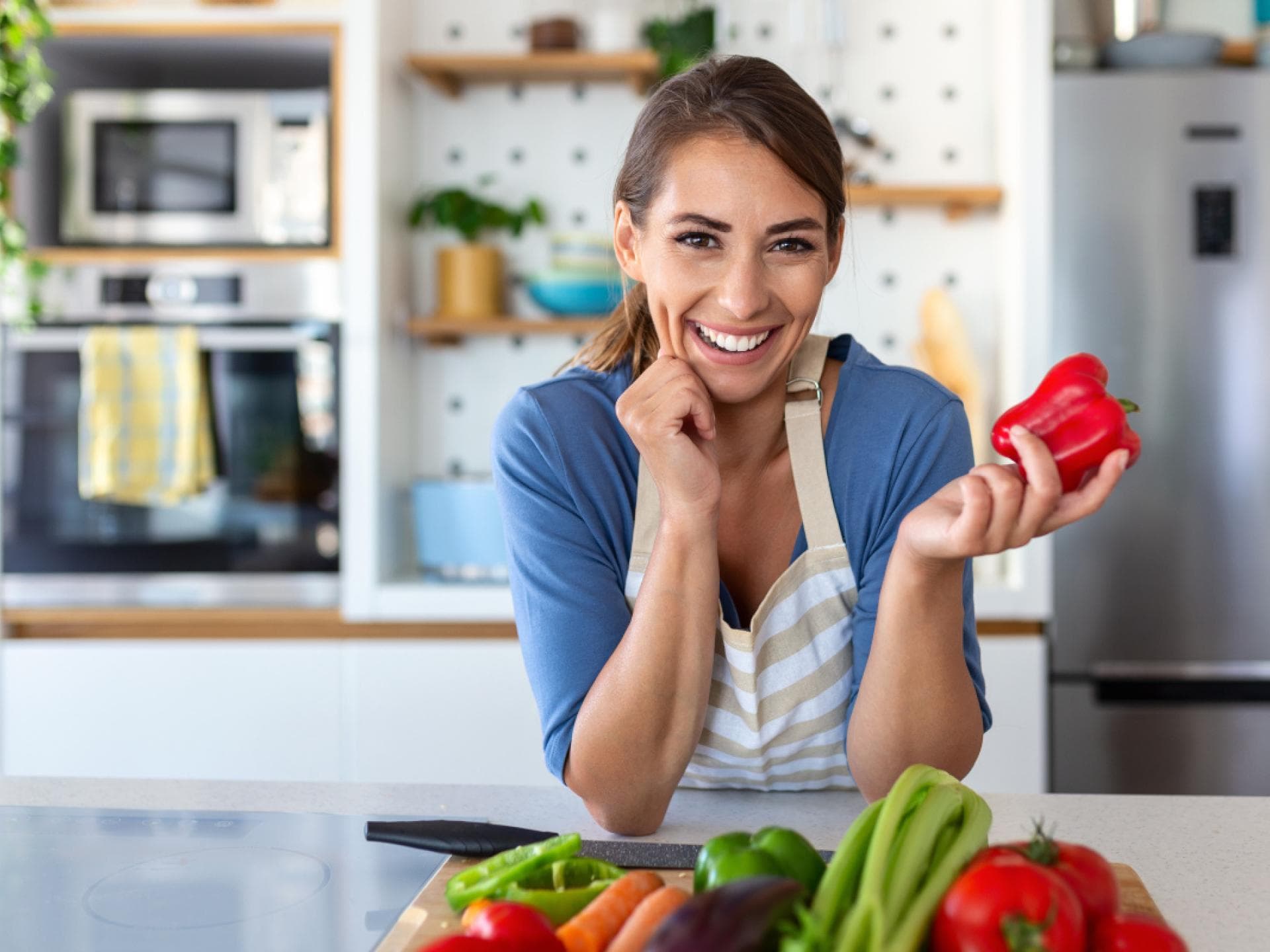 Frau in der Küche hält Paprika in den Händen Frau in der Küche hält Paprika in den Händen