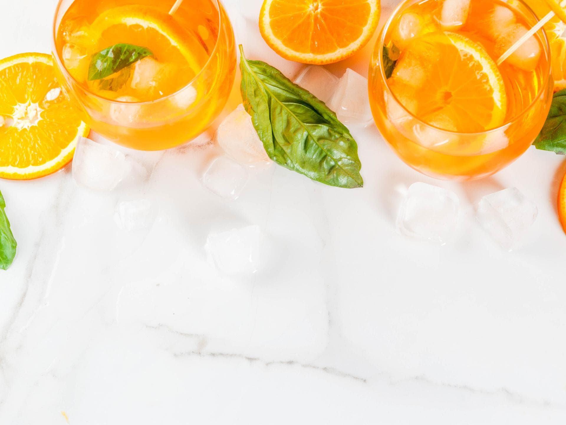Gläser mit Orangenlimonade und Basilikum zwischen Eiswürfeln. Gläser mit Orangenlimonade und Basilikum zwischen Eiswürfeln.