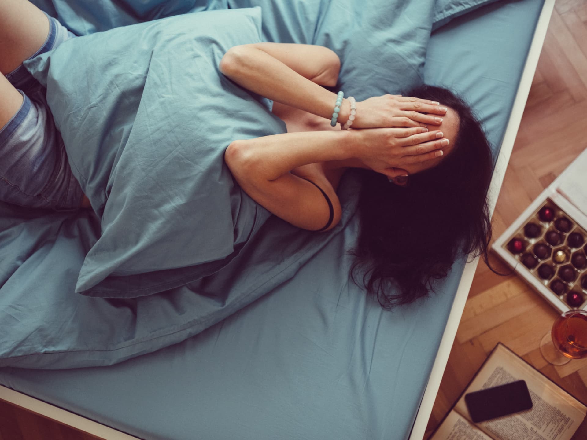 Frau liegt im Bett und weint