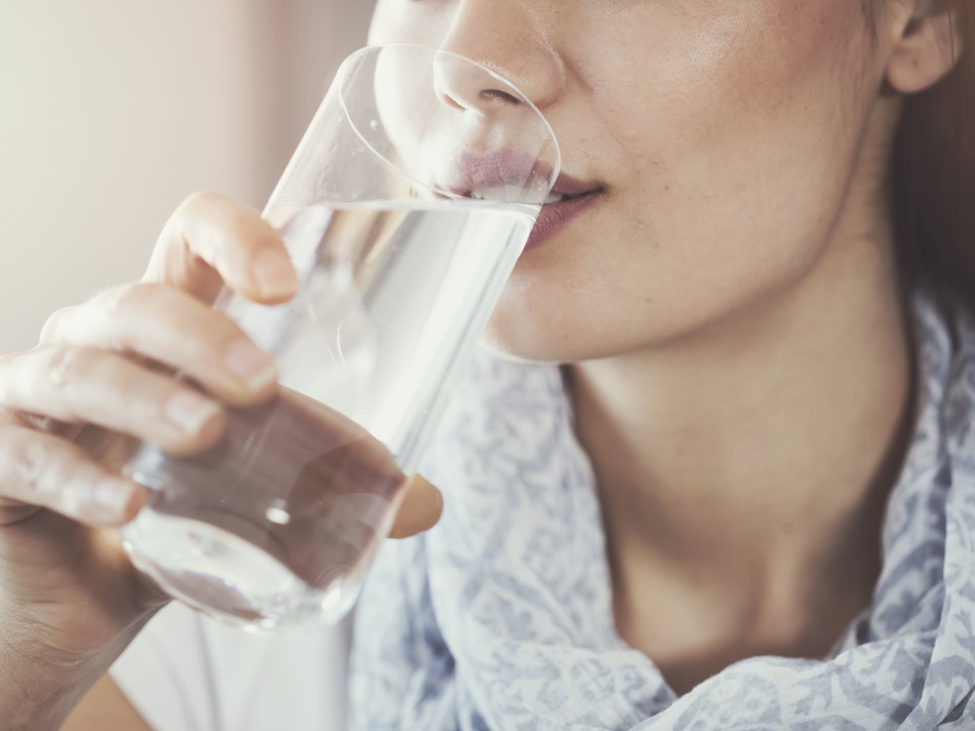Polydipsie ist ein Zustand, bei dem Betroffene übermäßig viel Wasser trinken. Frau trinkt Wasser