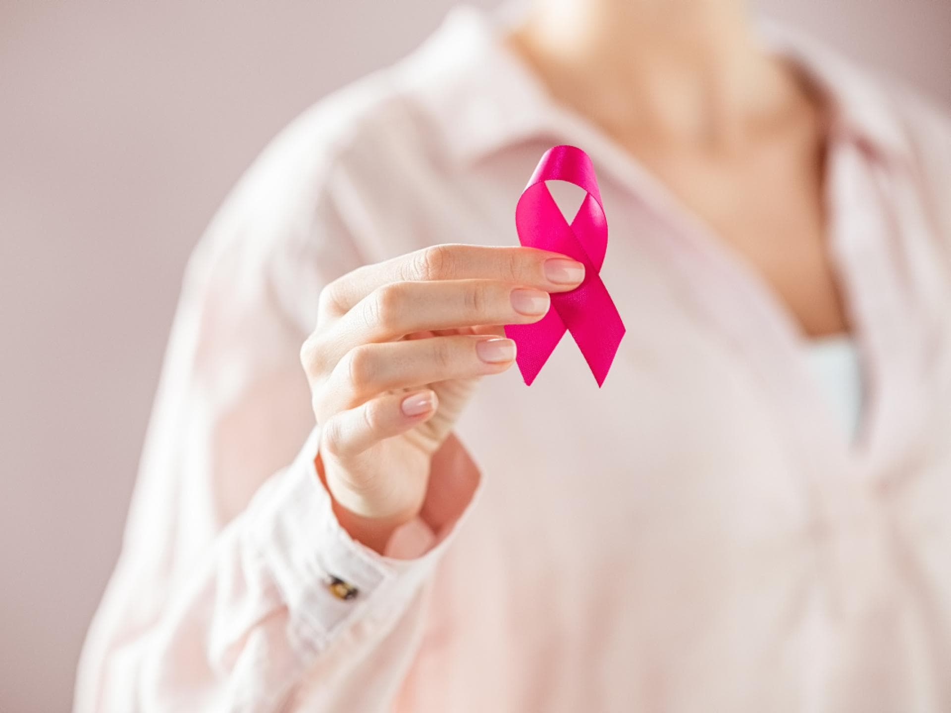 Frau hält pinke Schleifen in den Händen
