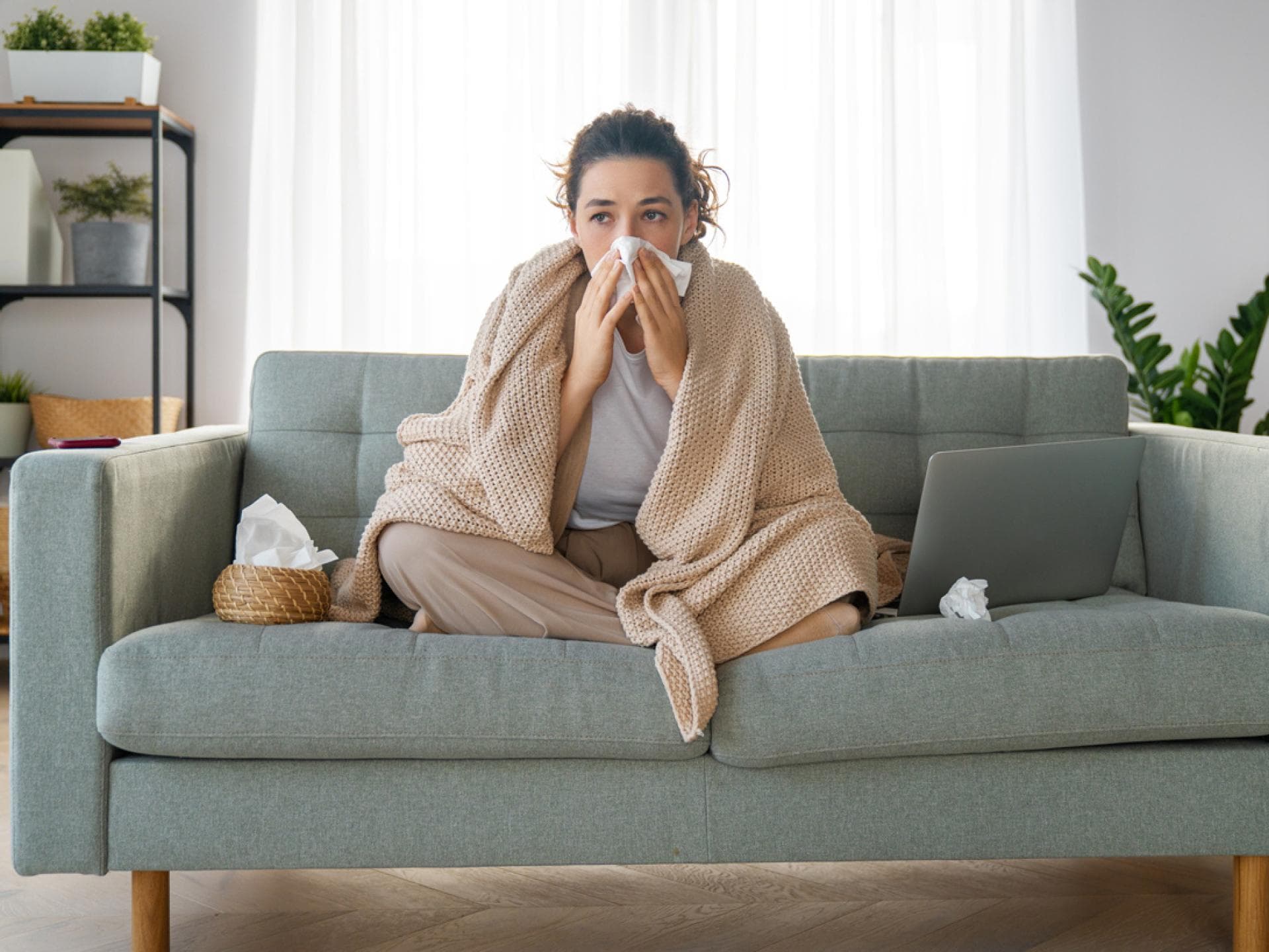 Erkältete Frau sitzt auf Sofa