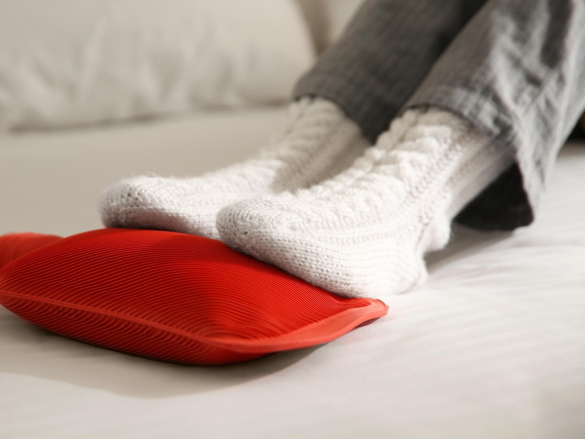 Füße in Socken liegen auf Wärmflasche