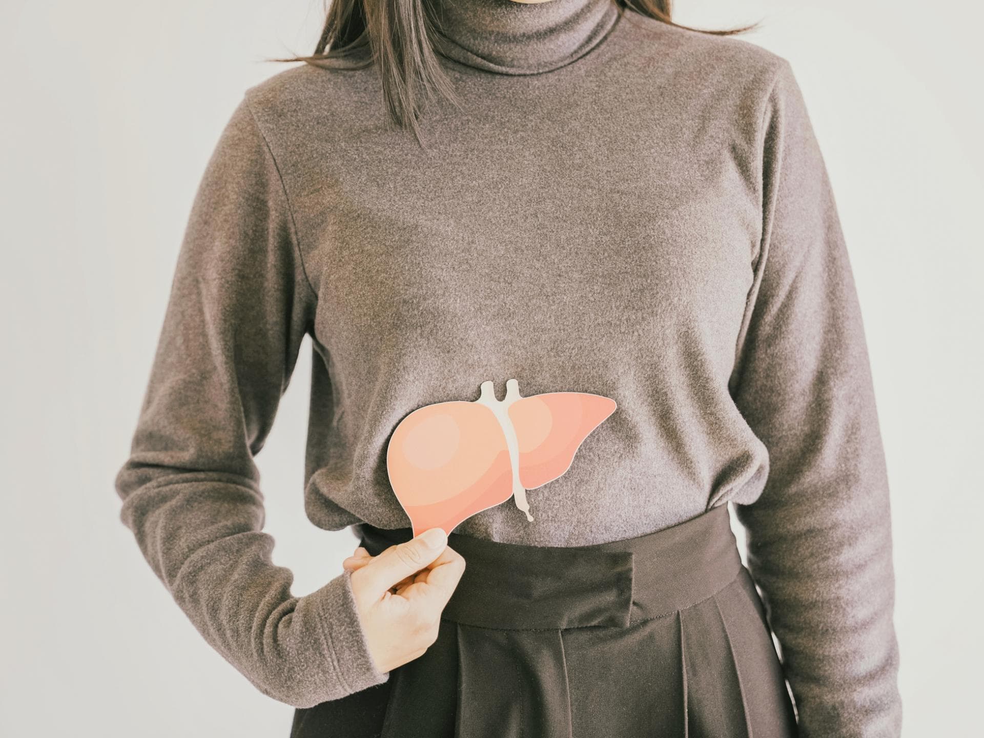 Hepatitisviren setzten sich auf der Leber ab und können Übles anrichten Eine junge Frau hält sich eine Niere aus Papier an die Stelle am Körper, wo sie sich befindet
