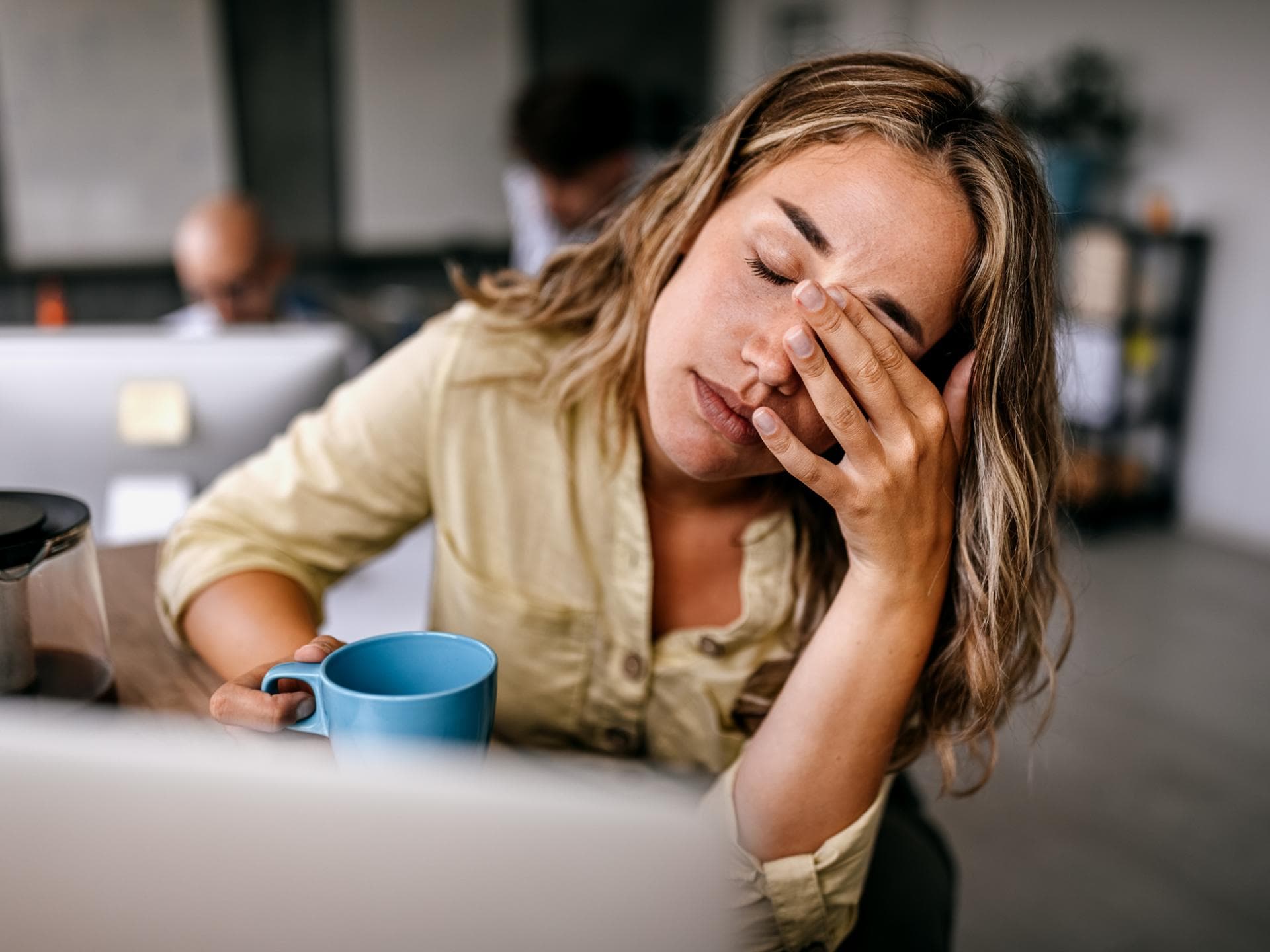 Eine Frau hält müde ihre Kaffeetasse fest