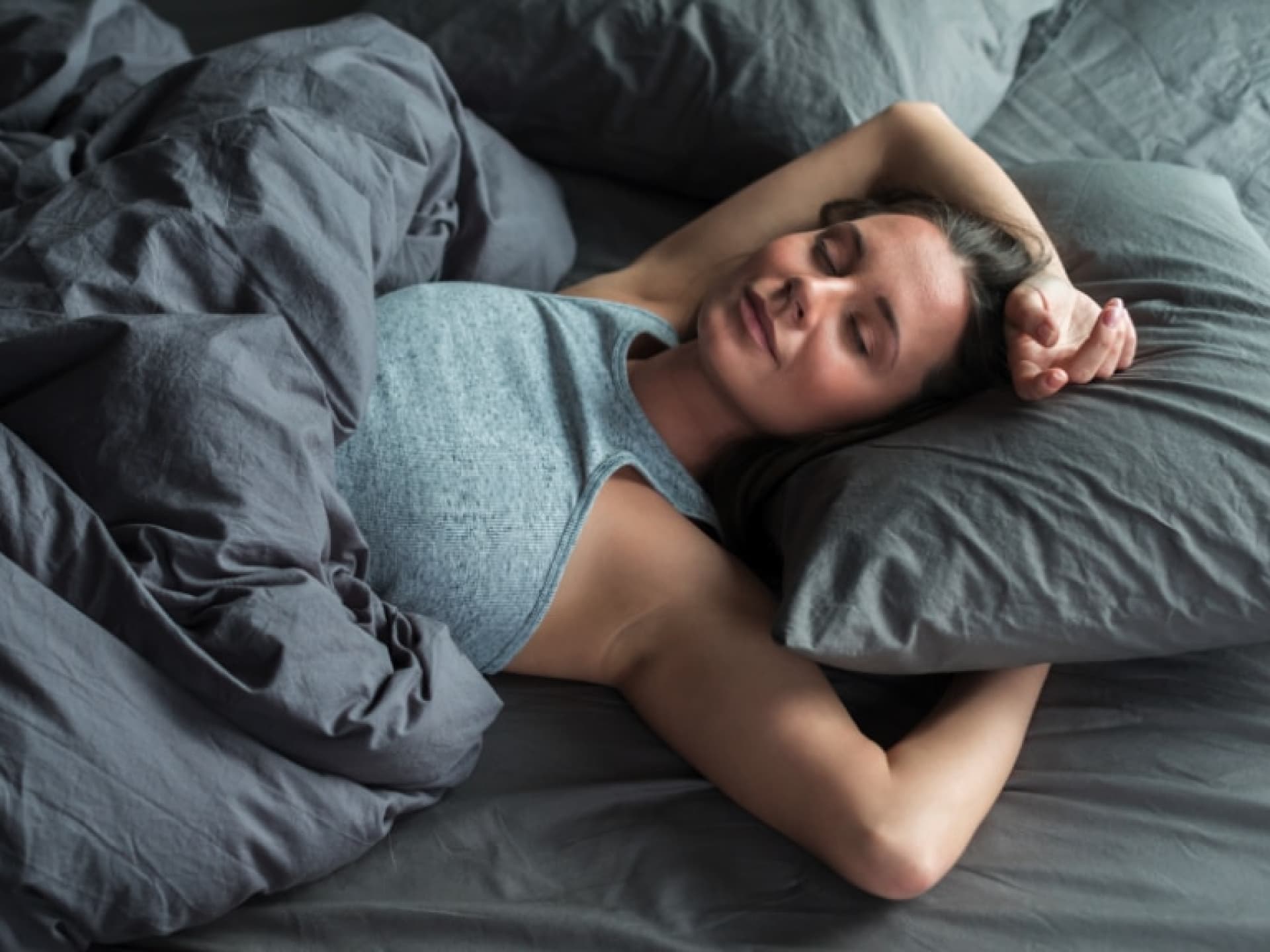 Eine Frau schläft erholt in ihrem Bett