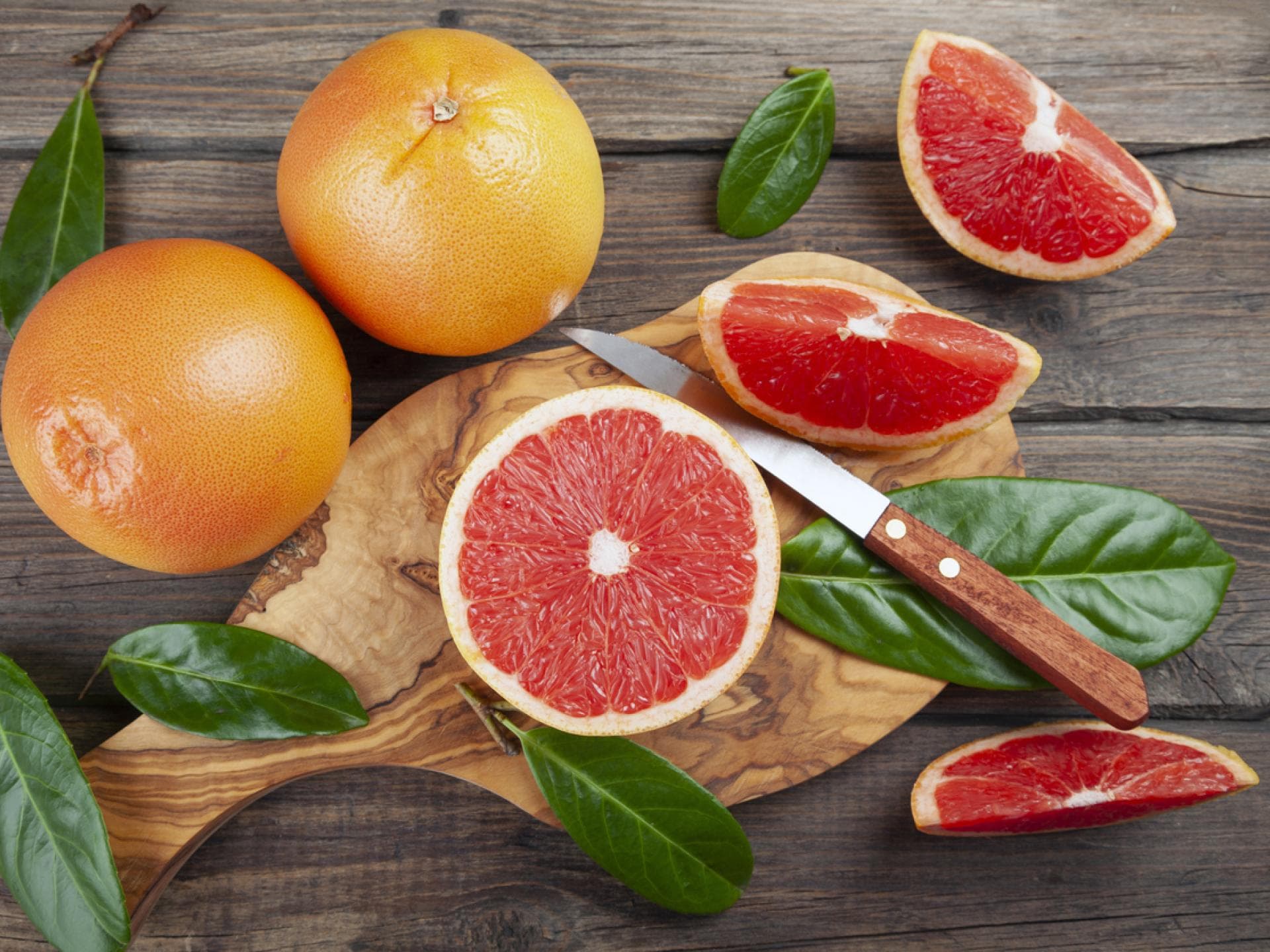 Grapefruit im Ganzen und aufgeschnitten mit einem Messer
