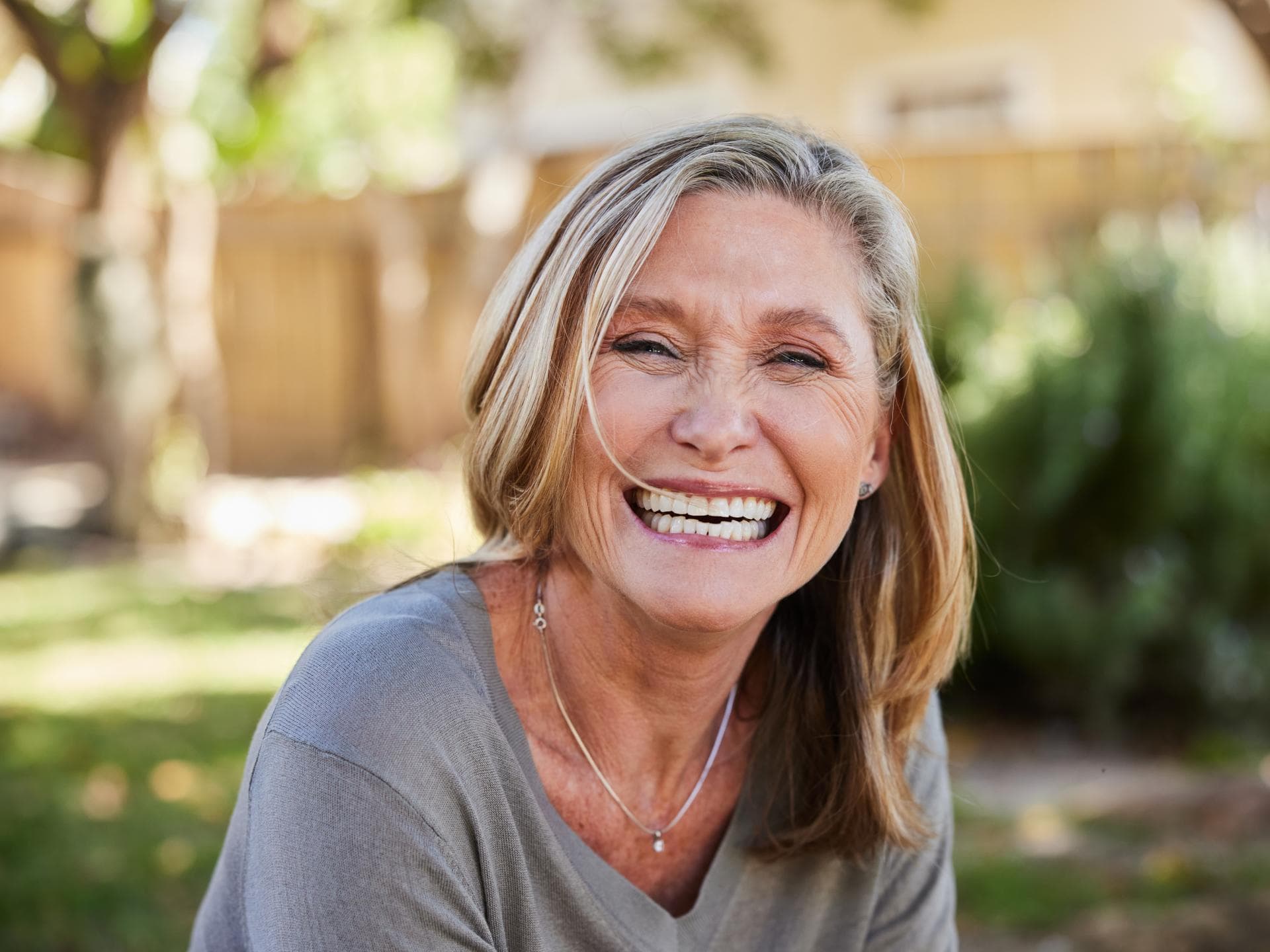 Krebsprävention durch Ernährung und Lifestyle Eine Frau im besten Alter strahlt mir einem breiten Lachen in die Kamera. Sie sieht gesund und glücklich aus.