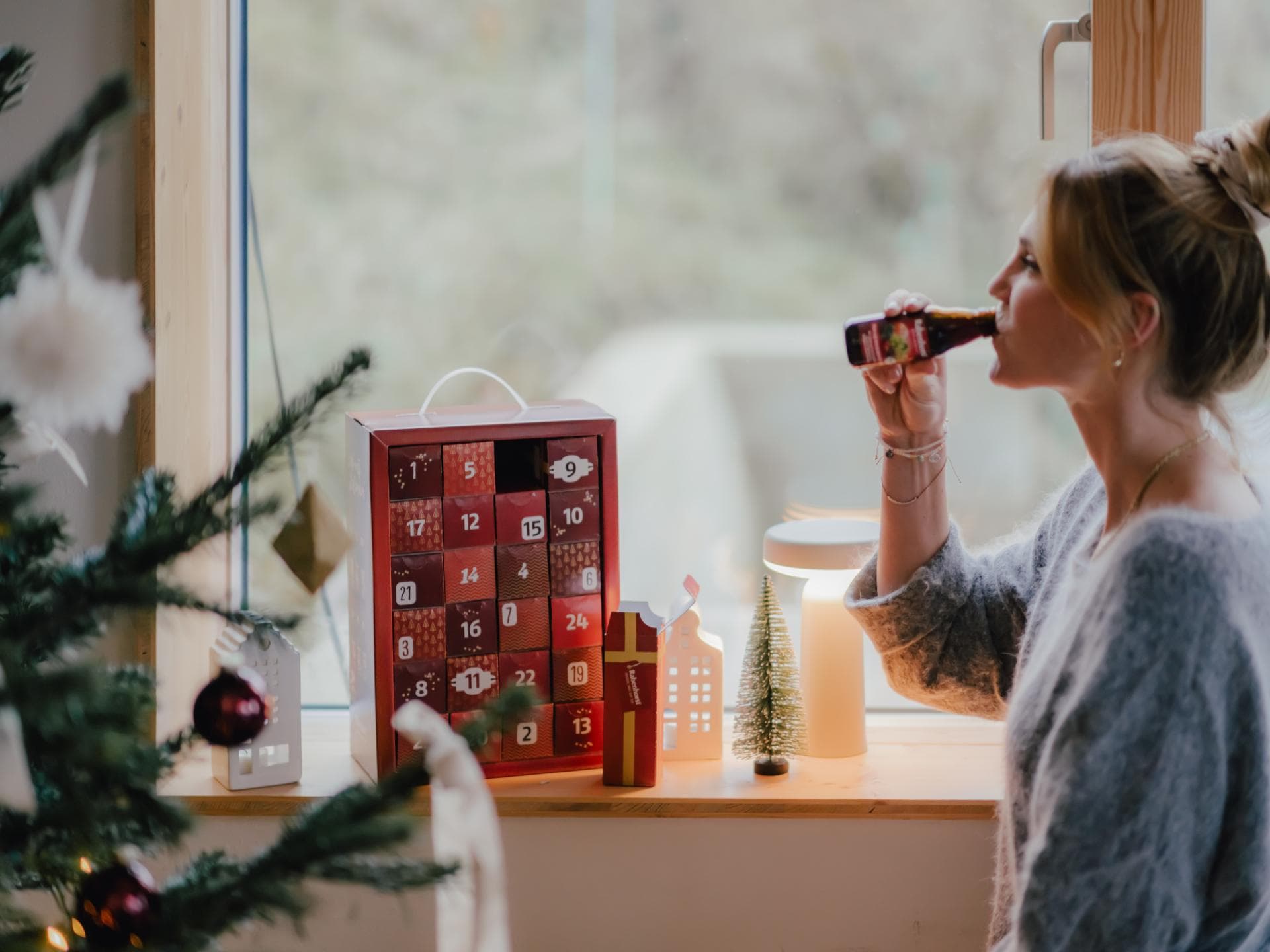 Rabenhorst-Adventskalender-Gewinnspiel Eine junge Frau hat das erste Türchen ihres Rabenhorst-Adventskalenders geöffnet und trinkt einen Schluck aus der Mini-Saftflasche