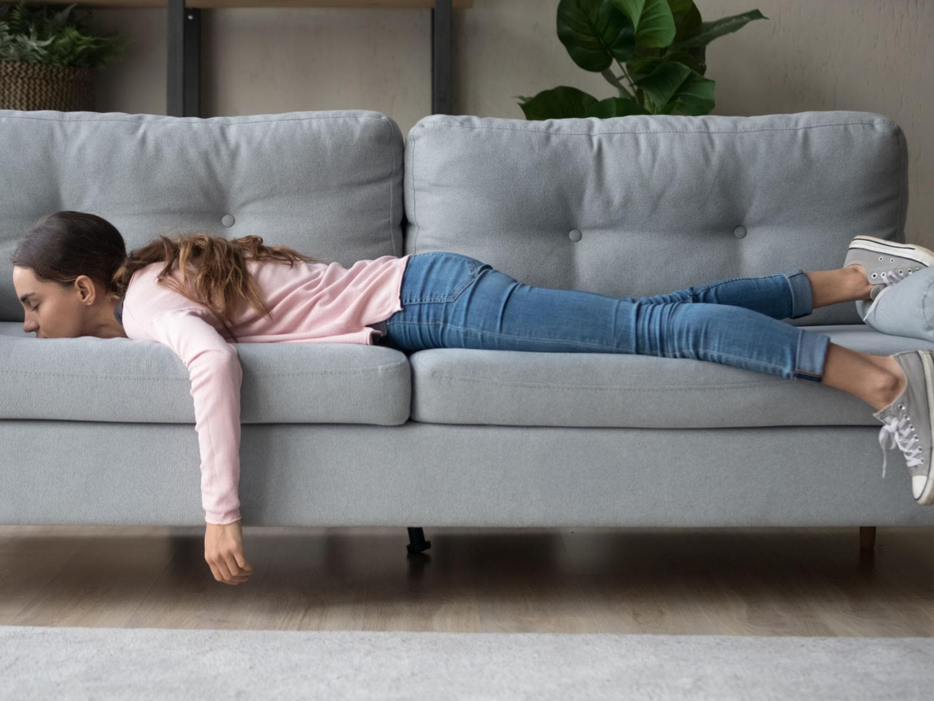 Boreout Symptom: Frau liegt bäuchlings auf dem Sofa