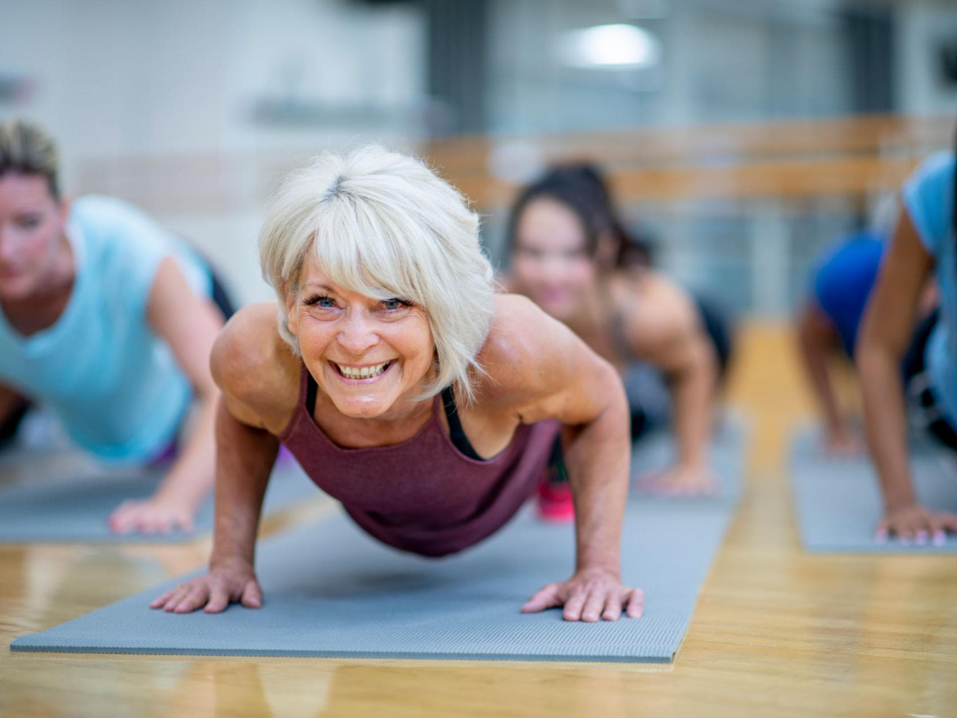 Ältere Frau im Sportkurs macht Liegestütze