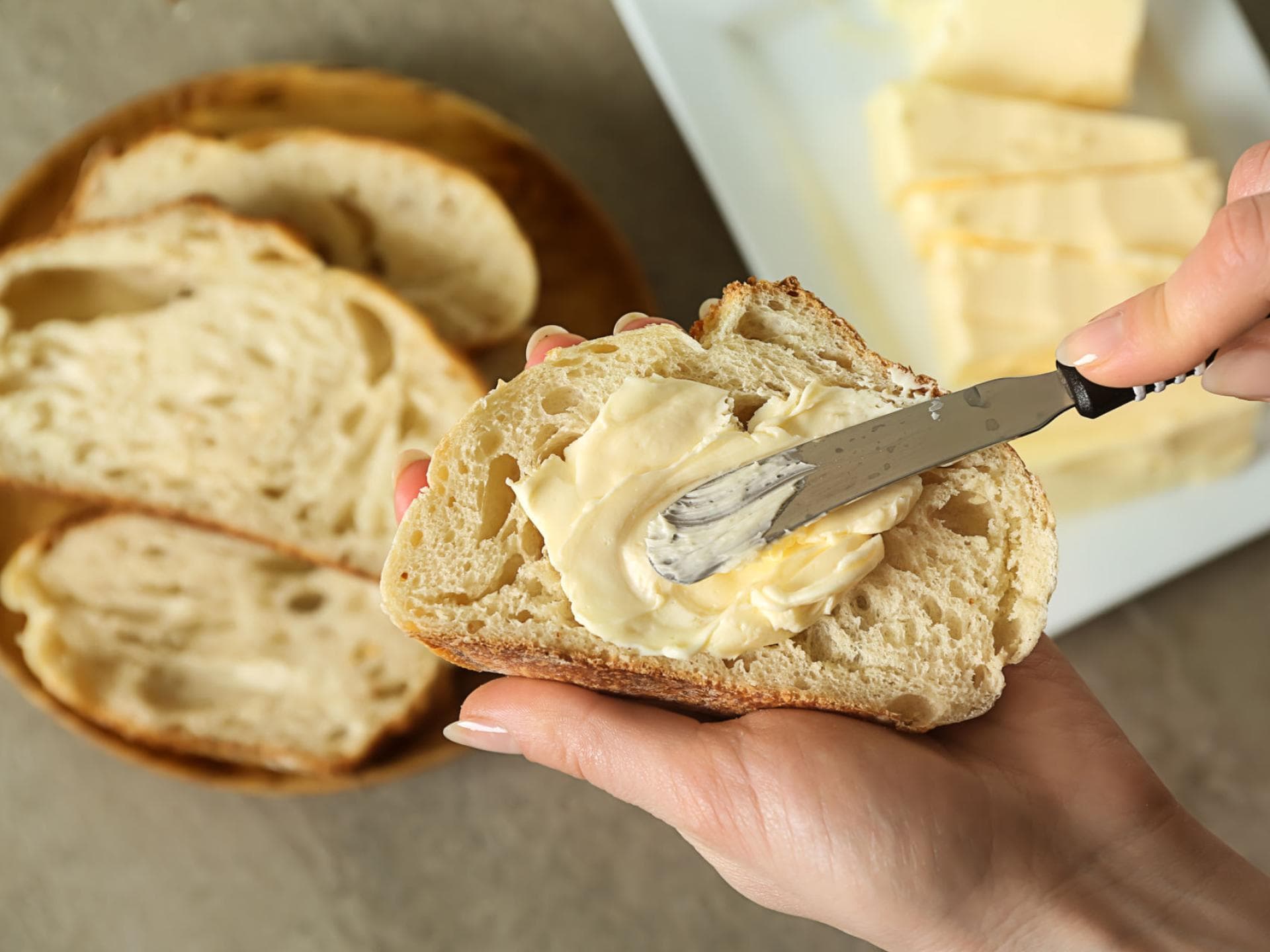 Frau schmiert Butter auf eine Scheibe Brot Frau schmiert Butter auf eine Scheibe Brot