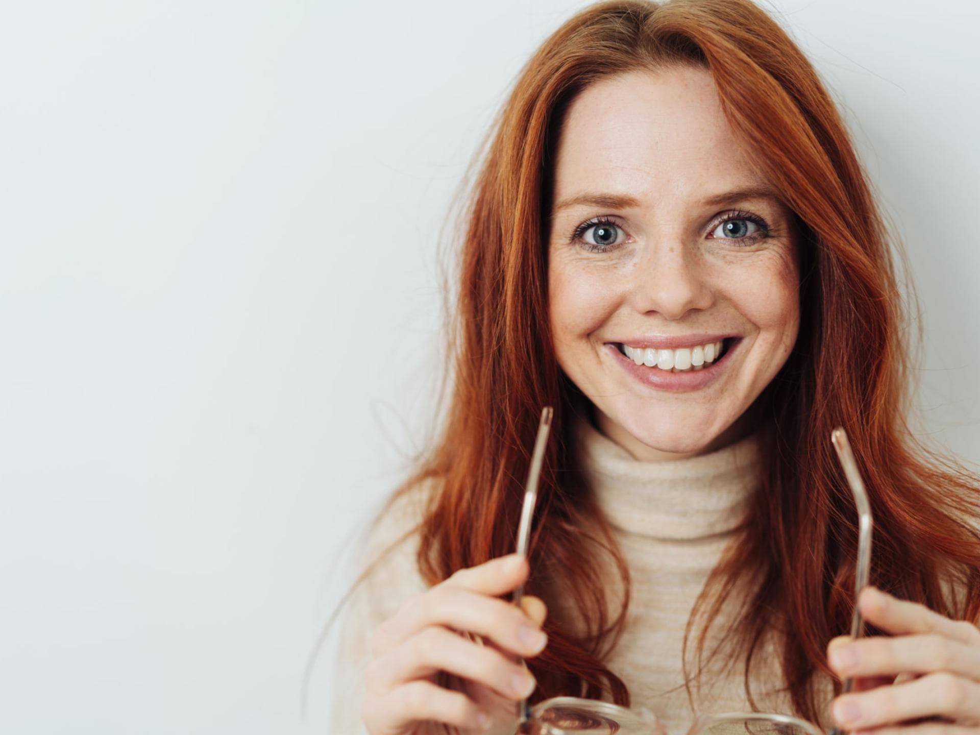 Frau mit strahlenden Augen und Brille in der Hand