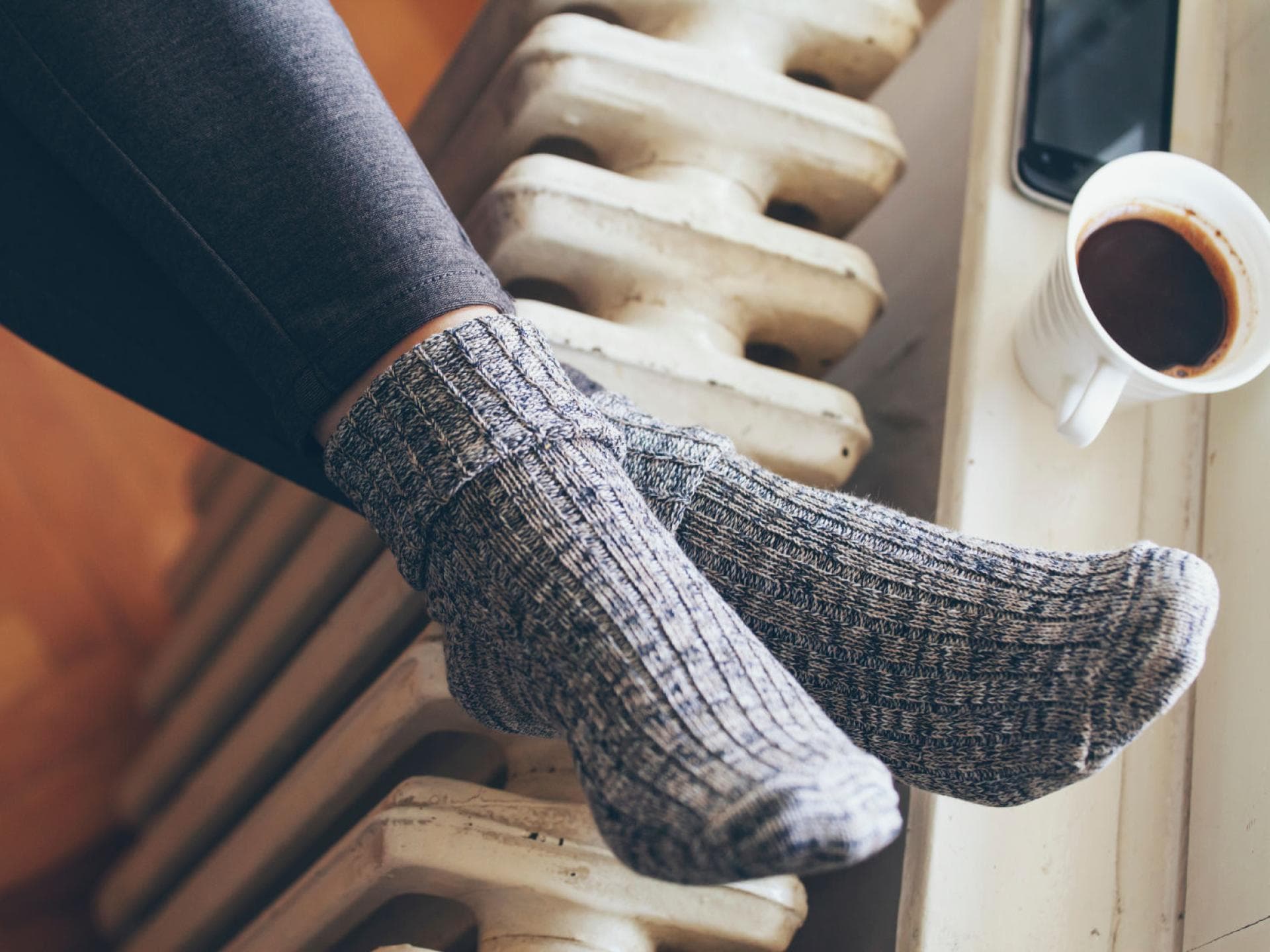 Frau mit Wollsocken Füße auf Heizung