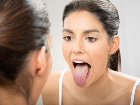 Frau guckt ihre Zunge an